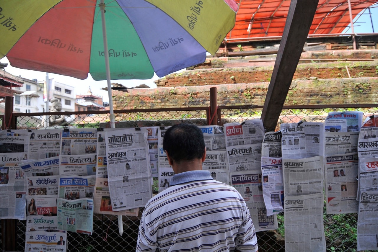 A man scans the front pages of newspapers at a kiosk in Basantapur Durbar Square, Kathmandu, Nepal, 25 August 2017, Narayan Maharjan/NurPhoto via Getty Images