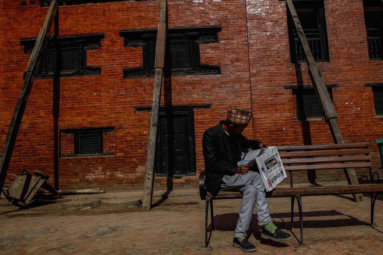 A man reads a newspaper early in the morning after his prayer at a temple on Nepali New Year Day, in Kathmandu, 14 April 2018, Sunil Pradhan/NurPhoto via Getty Images