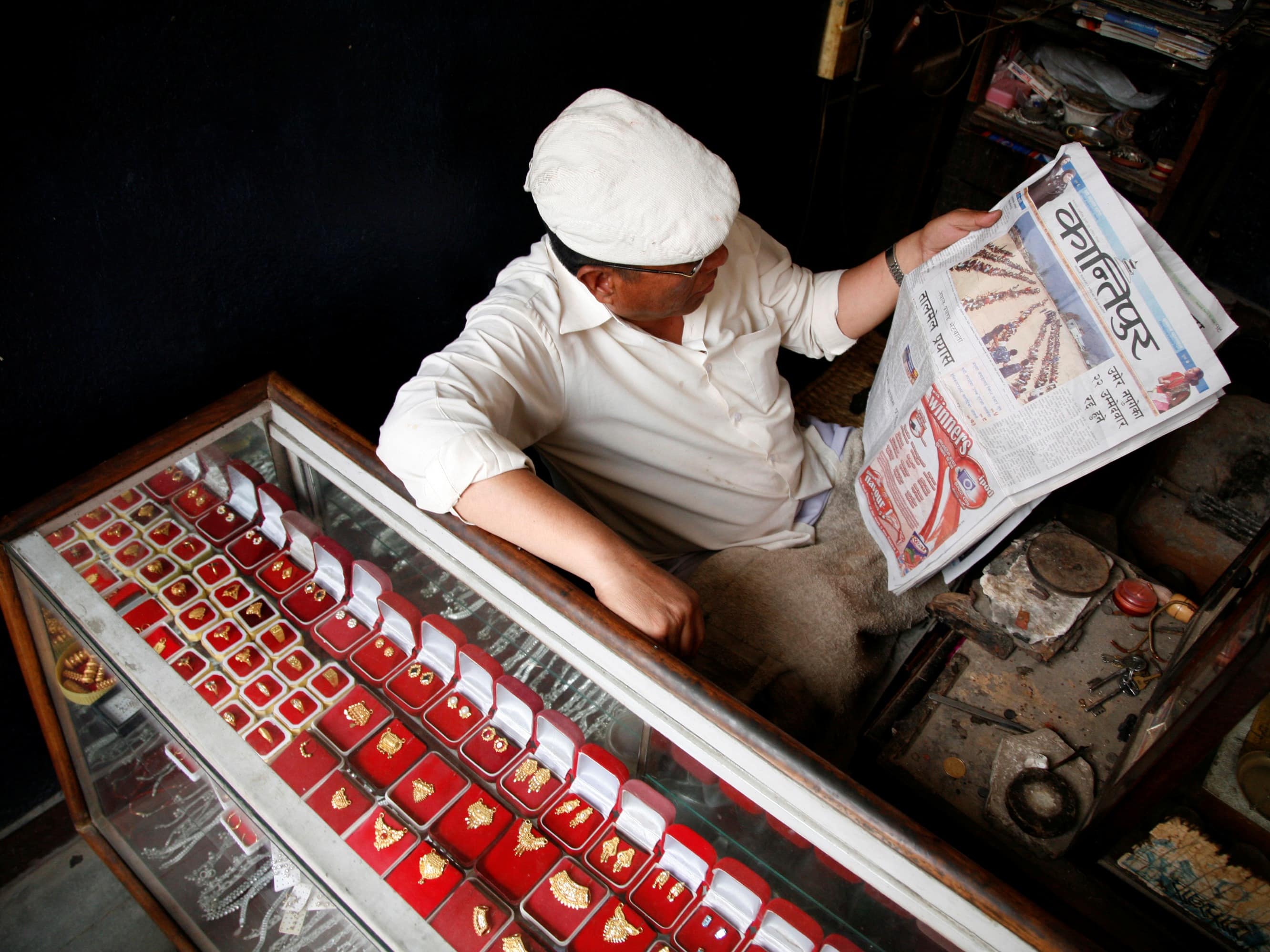 A goldsmith reads the "Kantipur Nepali Daily" newspaper in Kathmandu, REUTERS/Euan Denholm