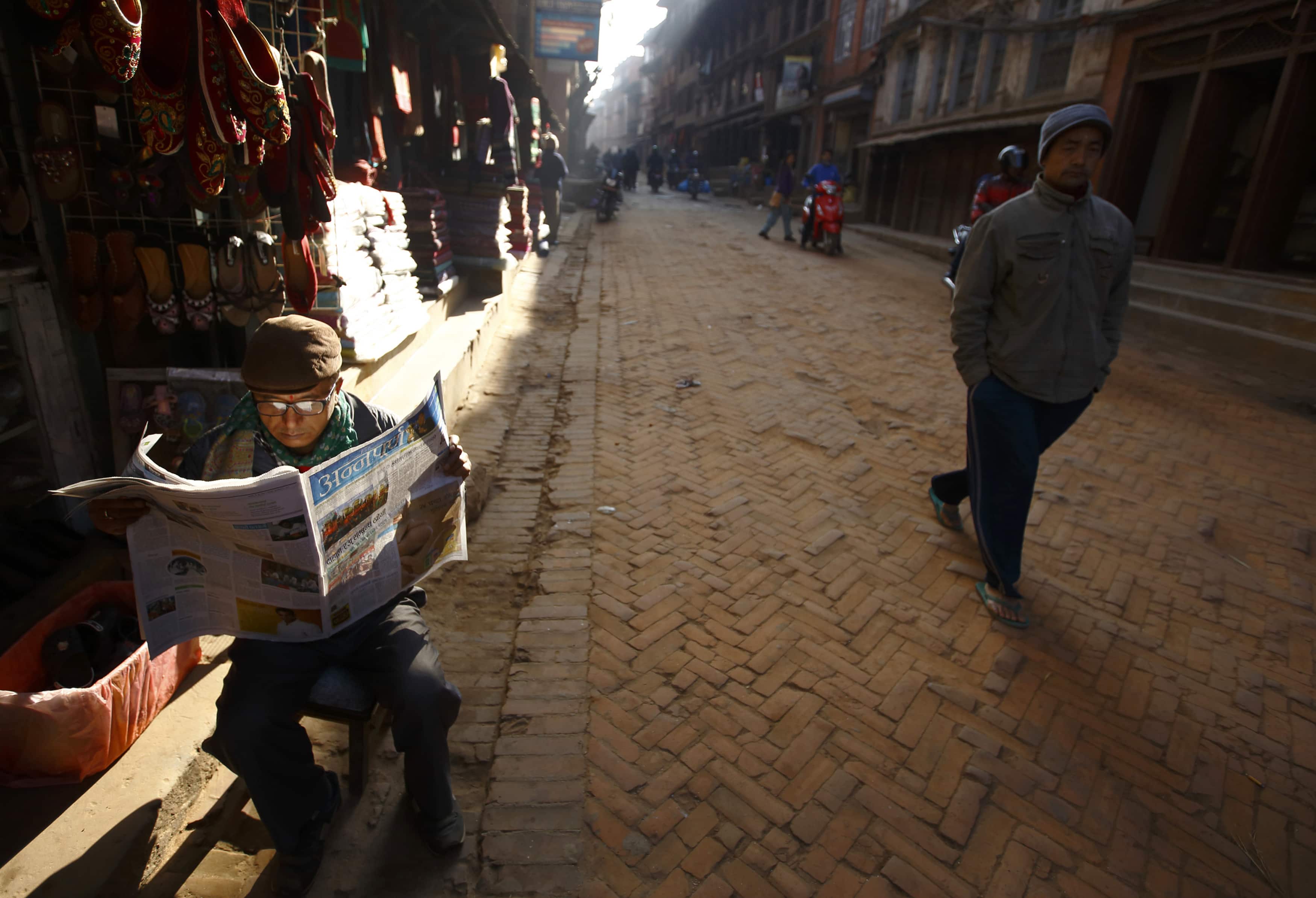 A man reads a newspaper outside his shop at the ancient city of Bhaktapur near Nepal's capital Kathmandu, 31 December 2013, REUTERS/Navesh Chitrakar