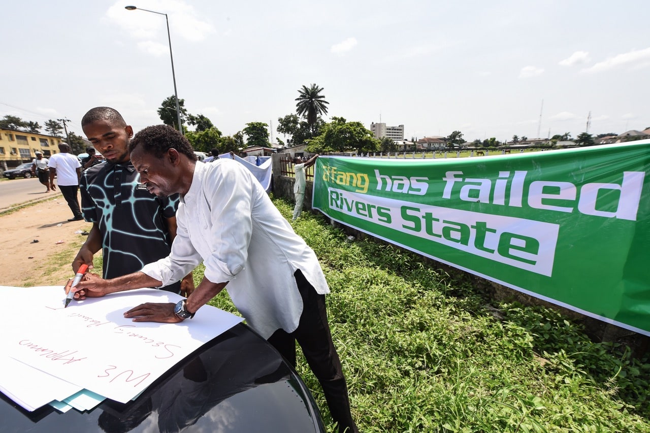 A man writes slogans on a placard on the sidelines of a demonstration held to protest against the suspension of governorship elections in Port Harcourt, Rivers State, Nigeria, 11 March 2019, PIUS UTOMI EKPEI/AFP/Getty Images