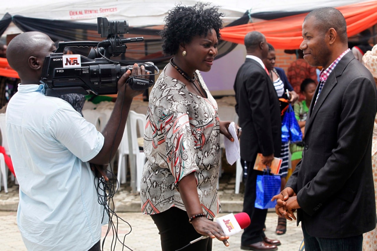 Television journalists from the Nigerian Television Authority (NTA) interview a man at an event in Lagos, 17 July 2014, REUTERS/Akintunde Akinleye