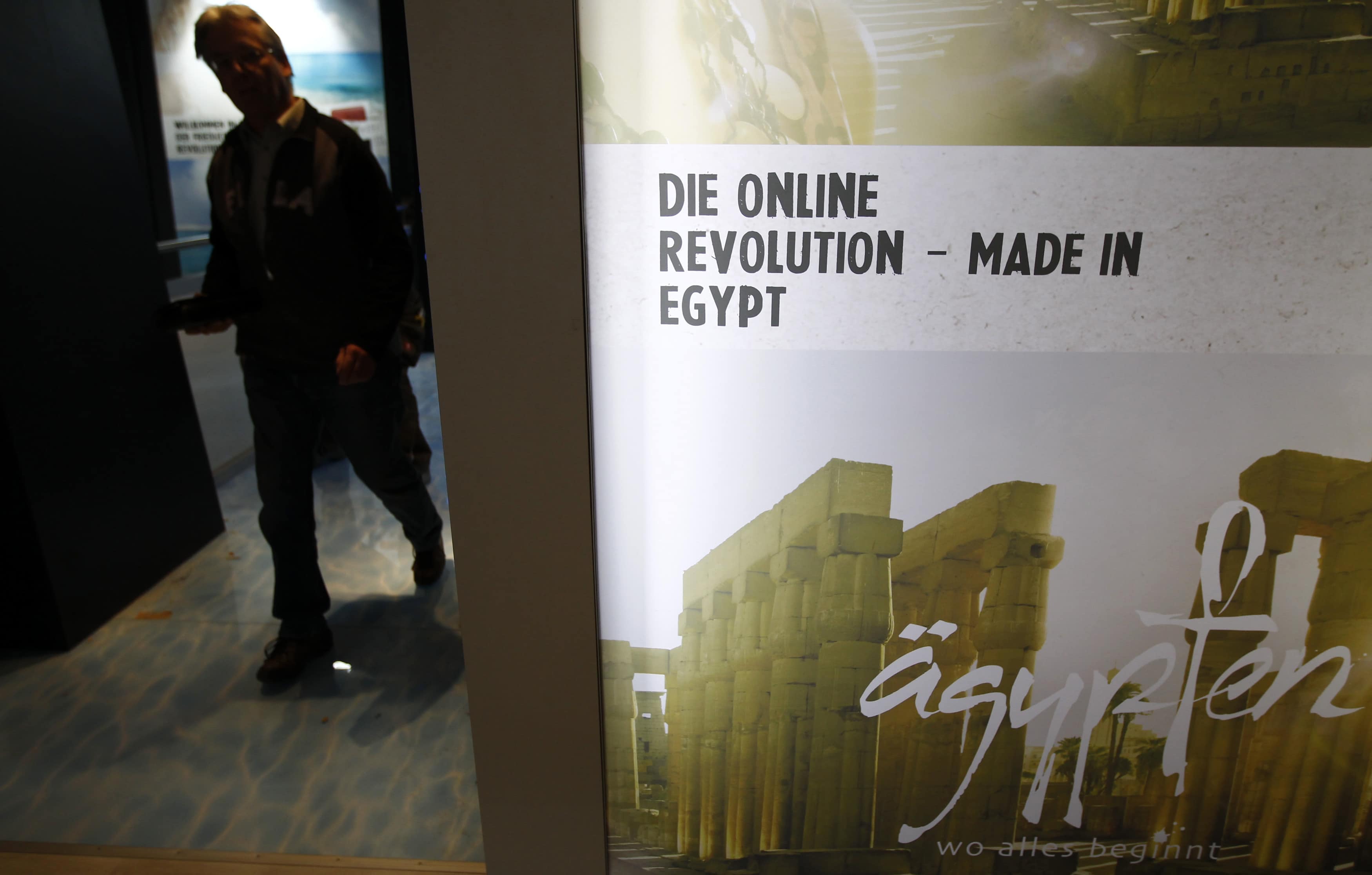 A worker walks next to a campaign poster referring to the political uprising in Egypt in Berlin in 2011. The banner reads, "The online revolution - Made in Egypt", REUTERS/Fabrizio Bensch