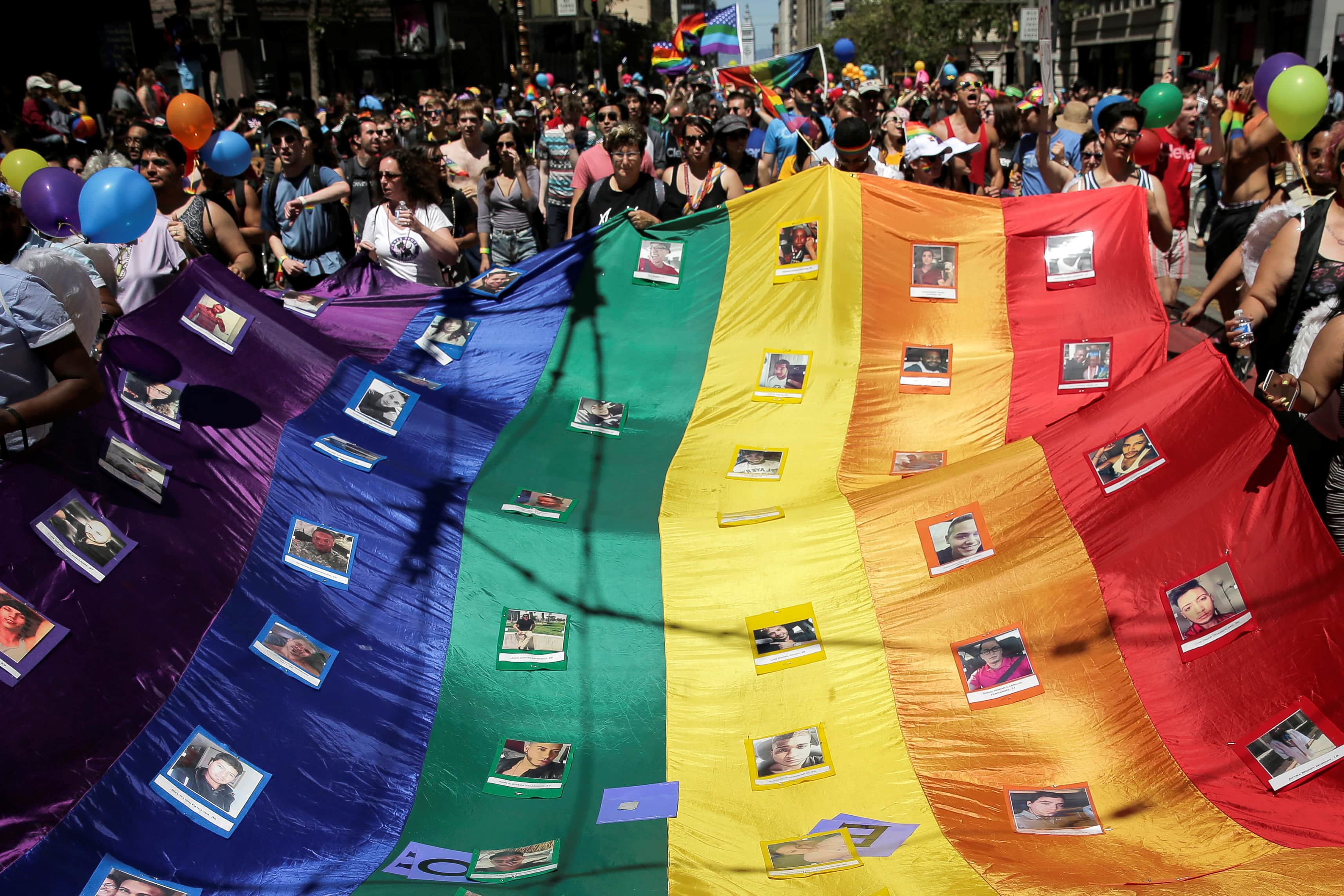 Marchers hold a rainbow flag with photos of the victims of the Orlando mass shooting during the San Francisco LGBT Pride Parade in San Francisco, California, U.S. June 26, 2016, REUTERS/Elijah Nouvelage