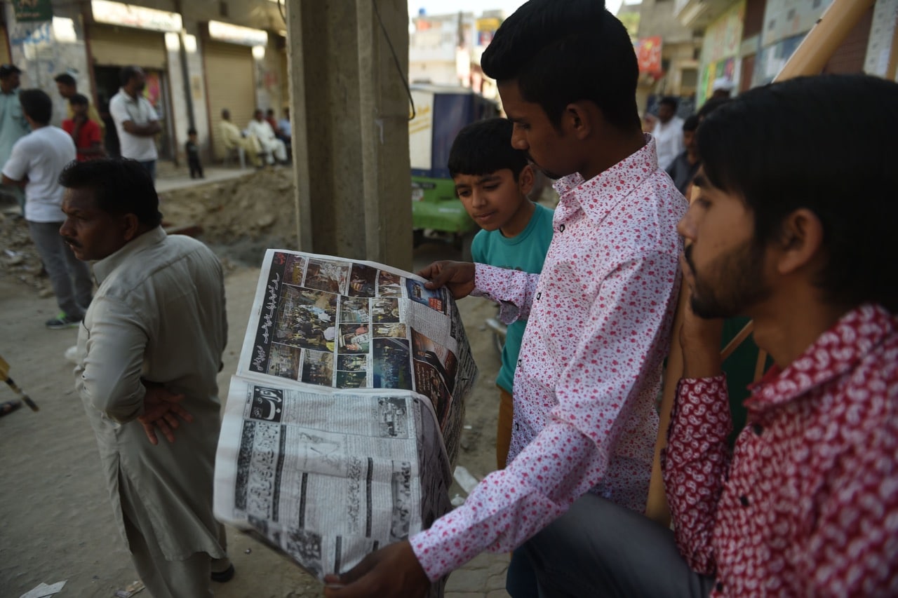 Pakistani men read newspapers on a street in Lahore, 28 March 2016, FAROOQ NAEEM/AFP/Getty Images