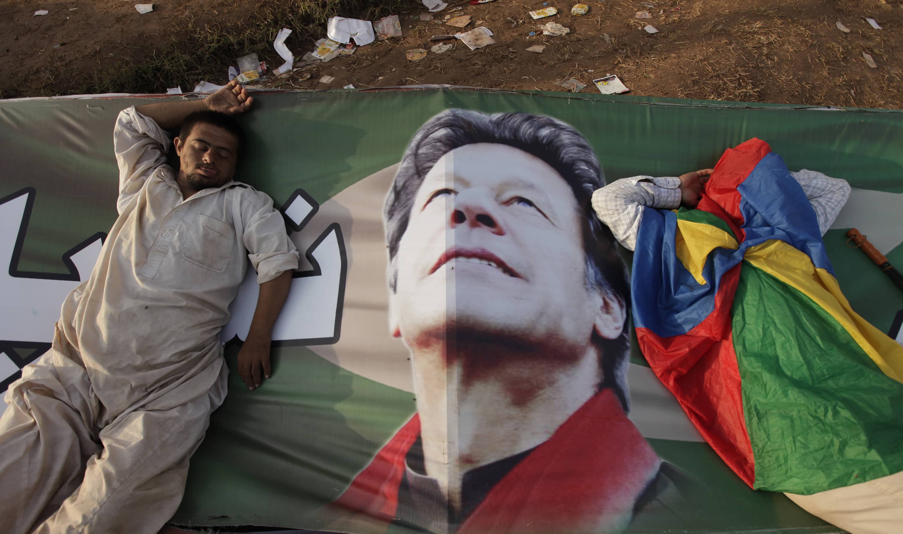 Supporters of Imran Khan, the Chairman of the Pakistan Tehreek-e-Insaf (PTI) political party, take a nap on Khan's campaign banner during what has been dubbed a "freedom march" in Islamabad, 25 August 2014, REUTERS/Faisal Mahmood