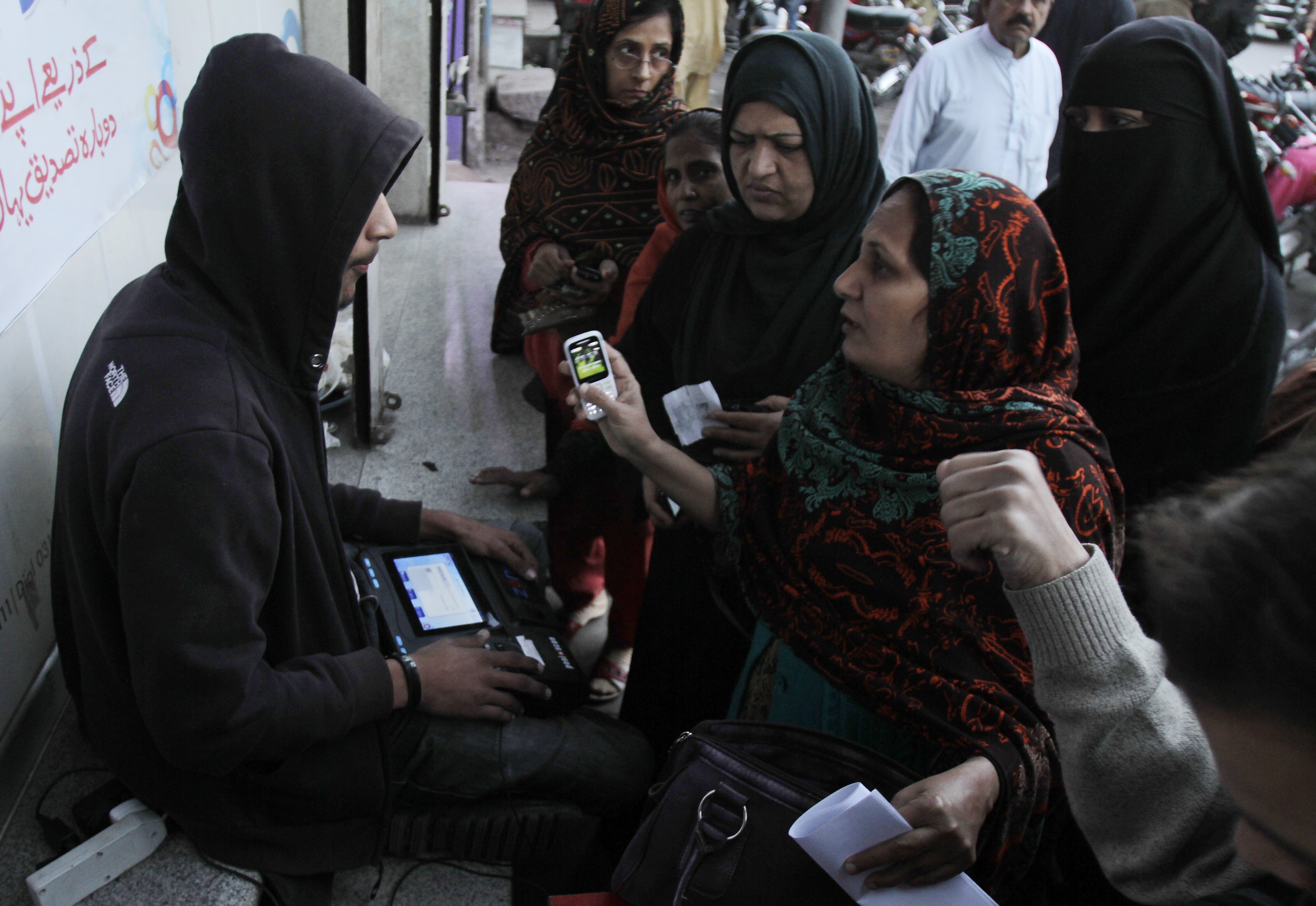 In this 25 February 2015 photo, people get their cell phone SIM cards verified in Lahore, Pakistan, AP Photo/K.M. Chaudary
