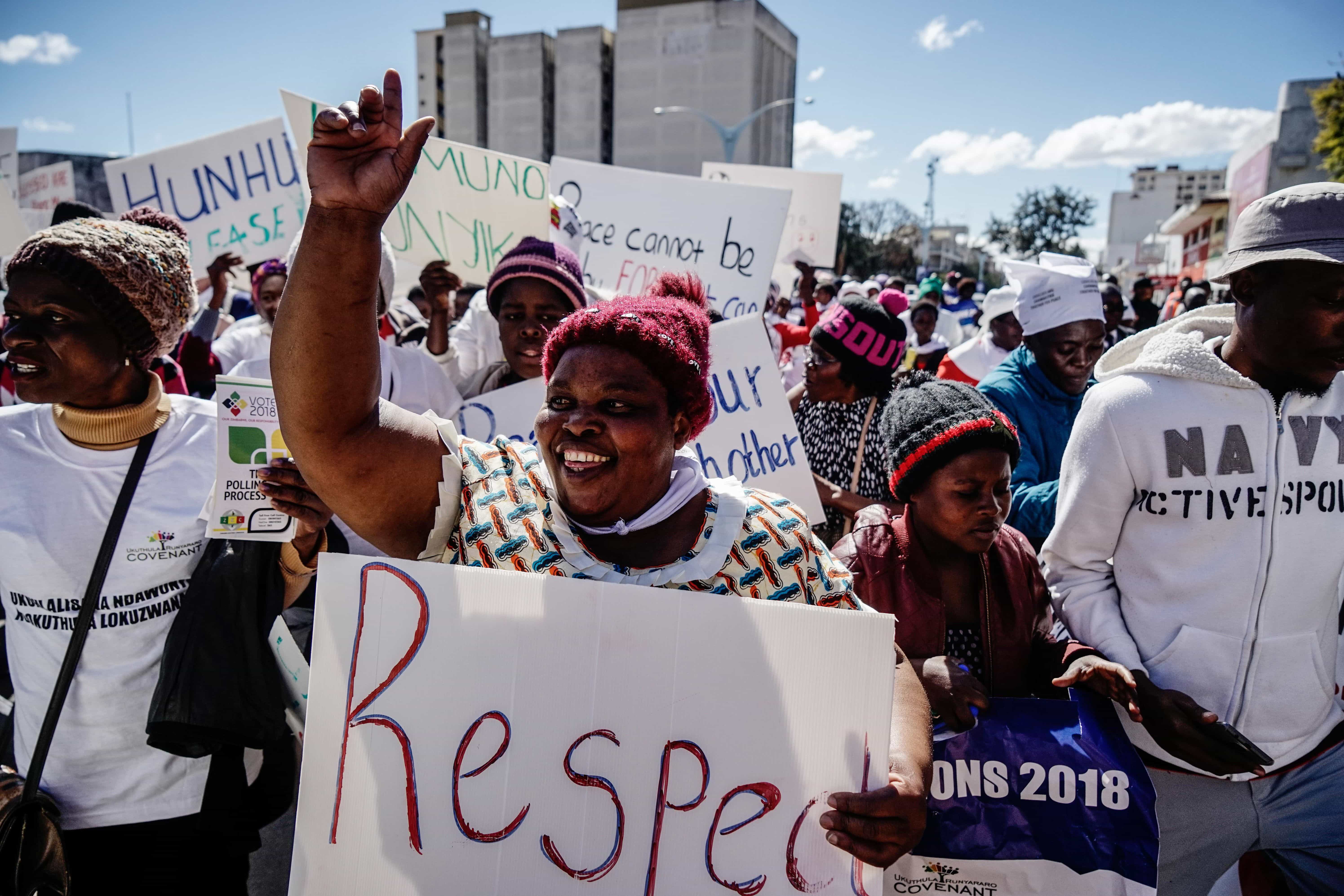 A demonstrator holds a placard as she takes part in a march for peace ahead of national elections, Bulawayo, Zimbabwe, 2018, ZINYANGE AUNTONY/AFP/Getty Images