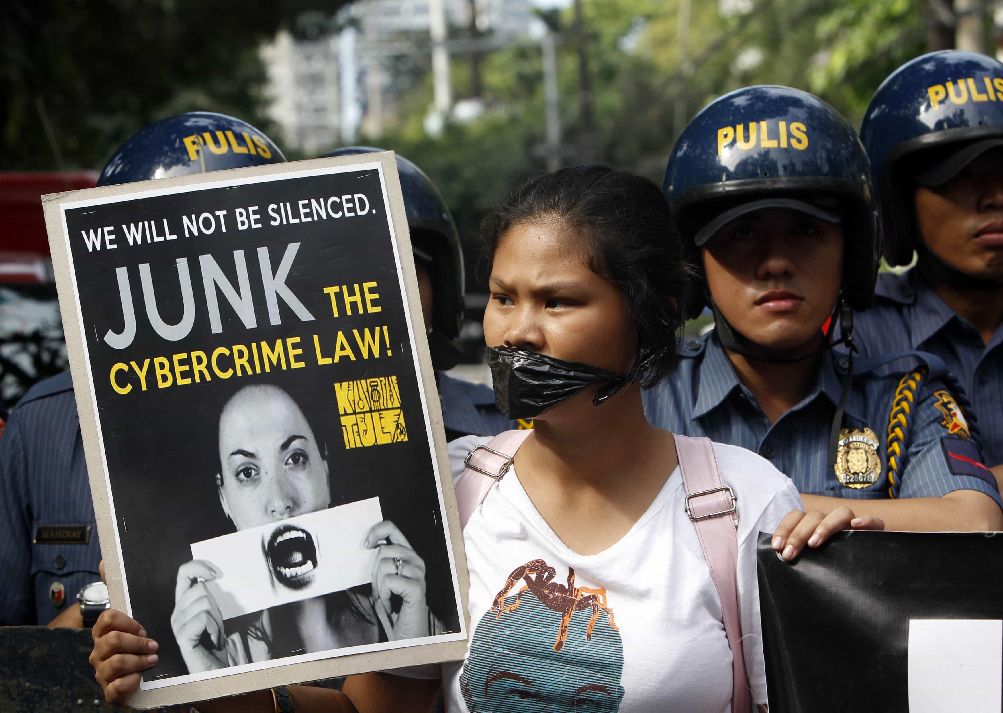 A netizen holds a placard in front of anti-riot policemen during a rally against the anti-cybercrime act in front of the Supreme Court in Manila, 15 January 2013, REUTERS/Romeo Ranoco