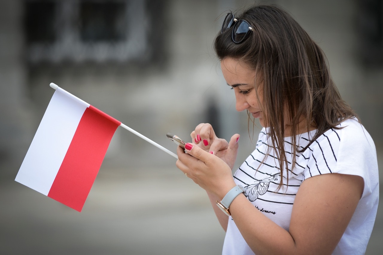 A woman checks her phone on Flag Day in Warsaw, Poland, 2 May 2018, Jaap Arriens/NurPhoto via Getty Images