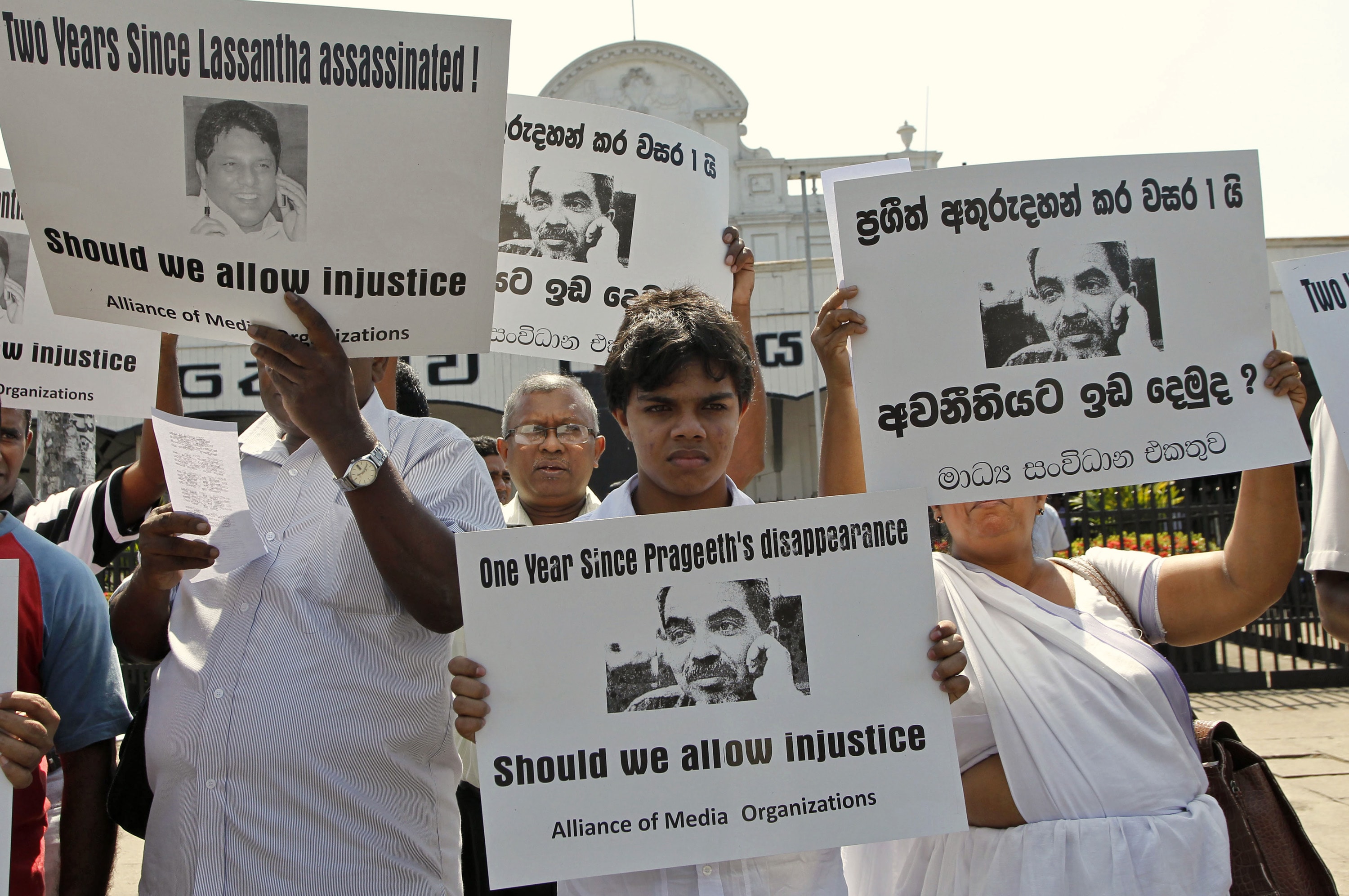 Son, center, and wife, right, of disappeared journalist Prageeth Ekneligoda hold his portrait during a protest in Colombo, Sri Lanka, on 18 January 2011, AP Photo/Eranga Jayawardena