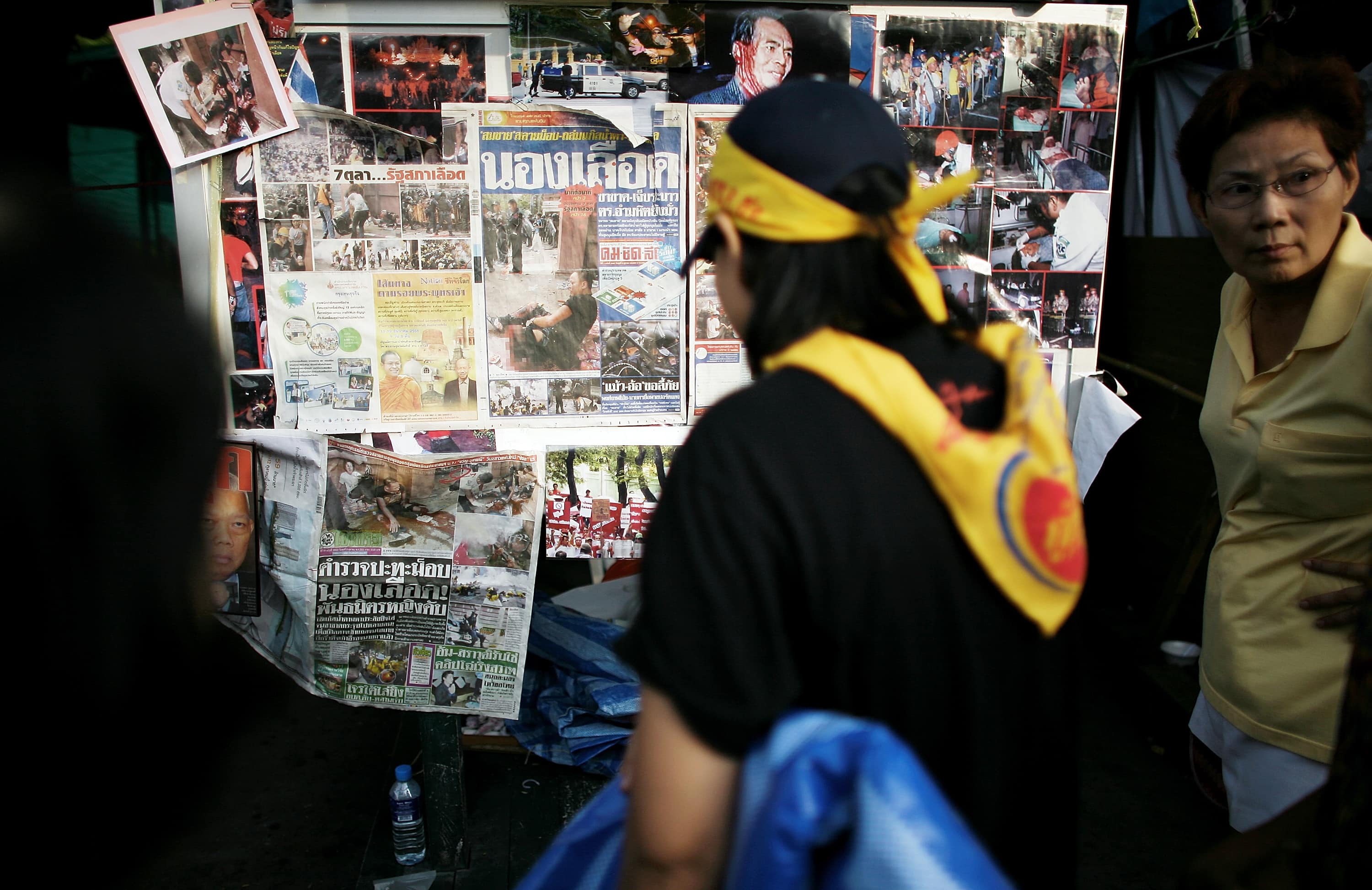 Anti-government protestors look at a newspaper board outside Government House in Bangkok, Thailand. 8 October 2008, Chumsak Kanoknan/Getty Images