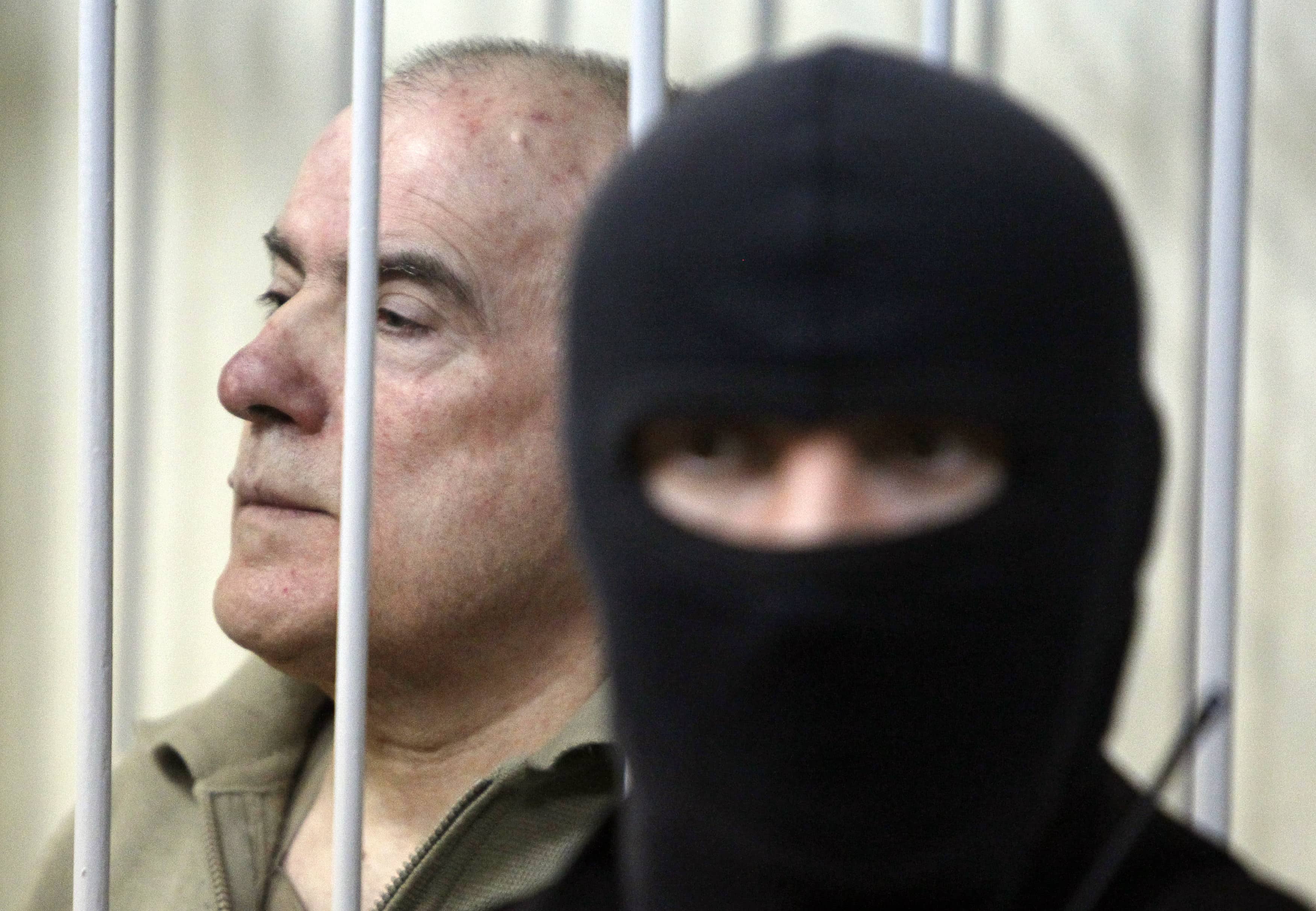 Former Interior Ministry General Aleksei Pukach looks out from a defendant's cage during a court session in Kiev on January 29, 2013, REUTERS/Gleb Garanich