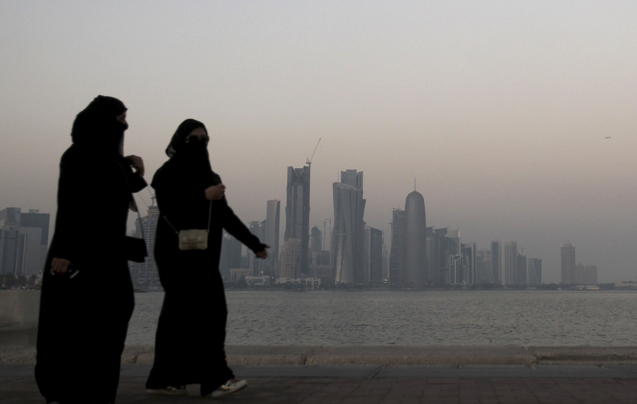 Women walk past buildings as the sun sets in Doha October 19, 2010. , REUTERS/Fadi Al-Assaad