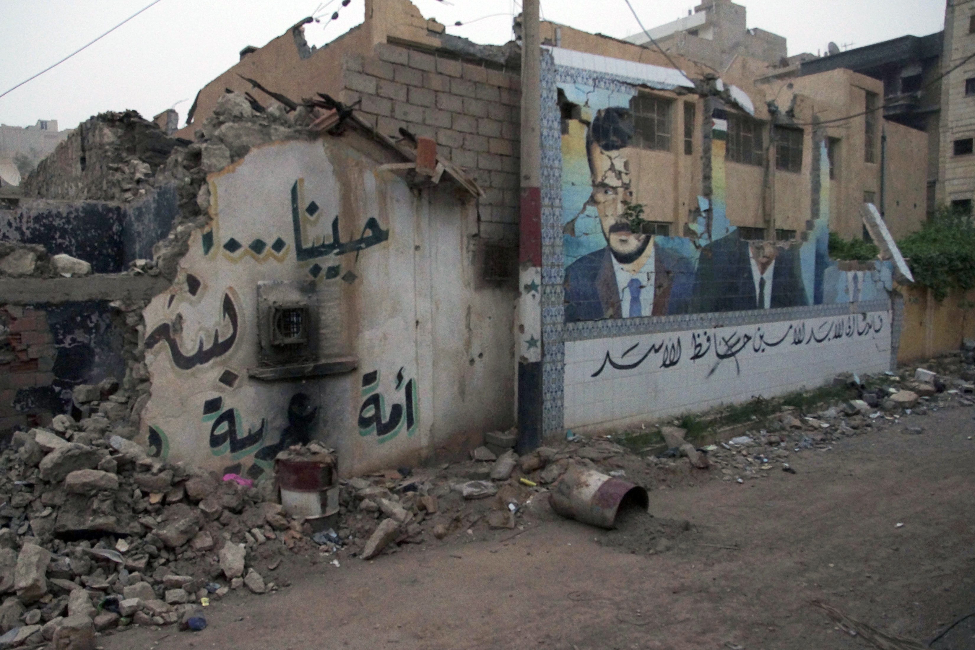 Defaced pictures of former Syrian President Hafez al-Assad (C) and the current President Bashar al-Assad, are seen on a damaged mural at a regime's security base after it was seized by rebel fighters in Deir al-Zor, REUTERS/ Khalil Ashawi