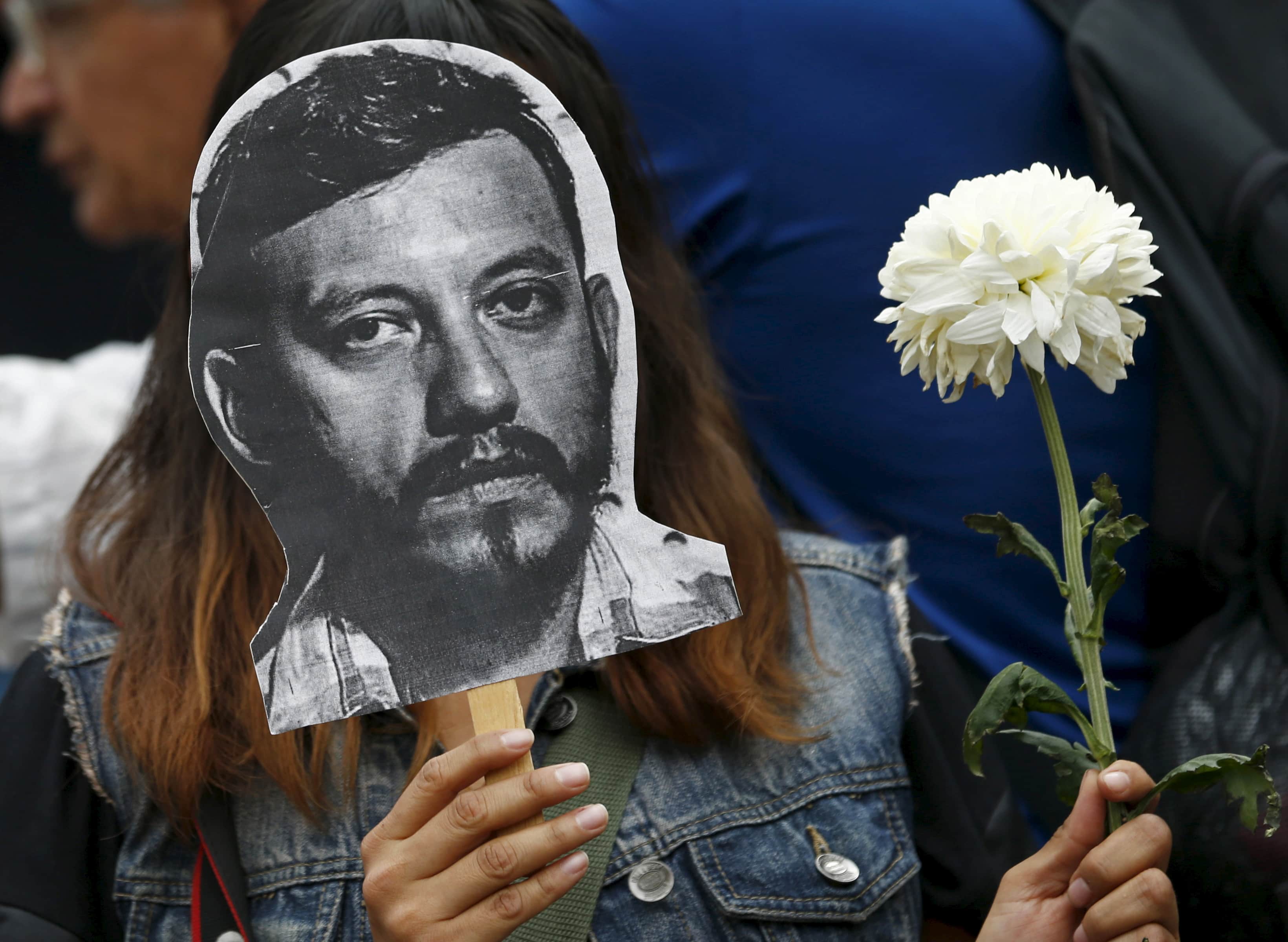 An activist holds up a picture of photojournalist Ruben Espinosa during a protest against his murder at the Angel of Independence monument in Mexico City, Mexico August 2, 2015, REUTERS/Henry Romero