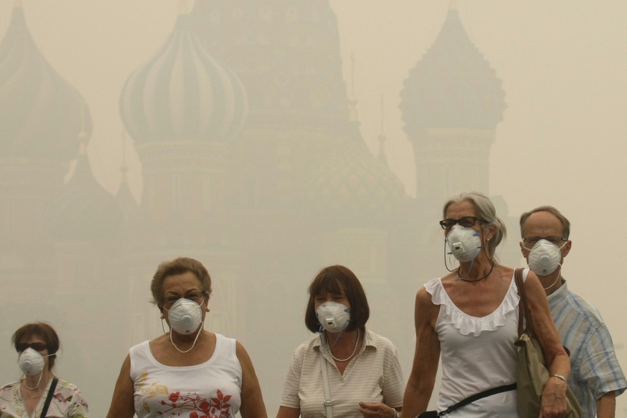 A thick blanket of smog, resulting from a wave of wildfires raging across Russia, forces tourists to wear masks as they walk along Red Square in Moscow, 6 August 2010, AP Photo/Mikhail Metzel, file