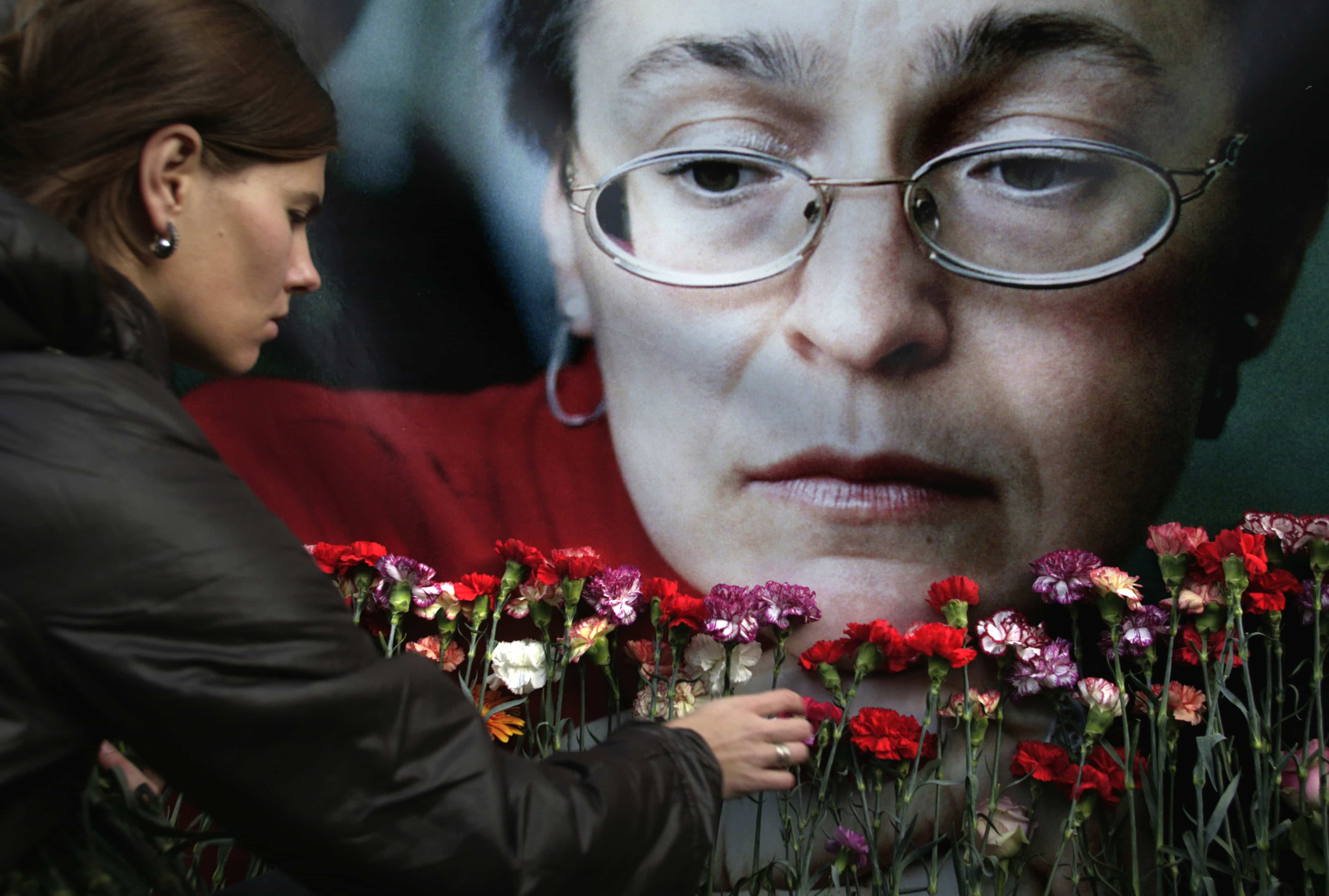 A woman places flowers before a portrait of slain Russian journalist Anna Politkovskaya, in Moscow, on 7 October 2009., AP Photo/Pavel Golovkin, File