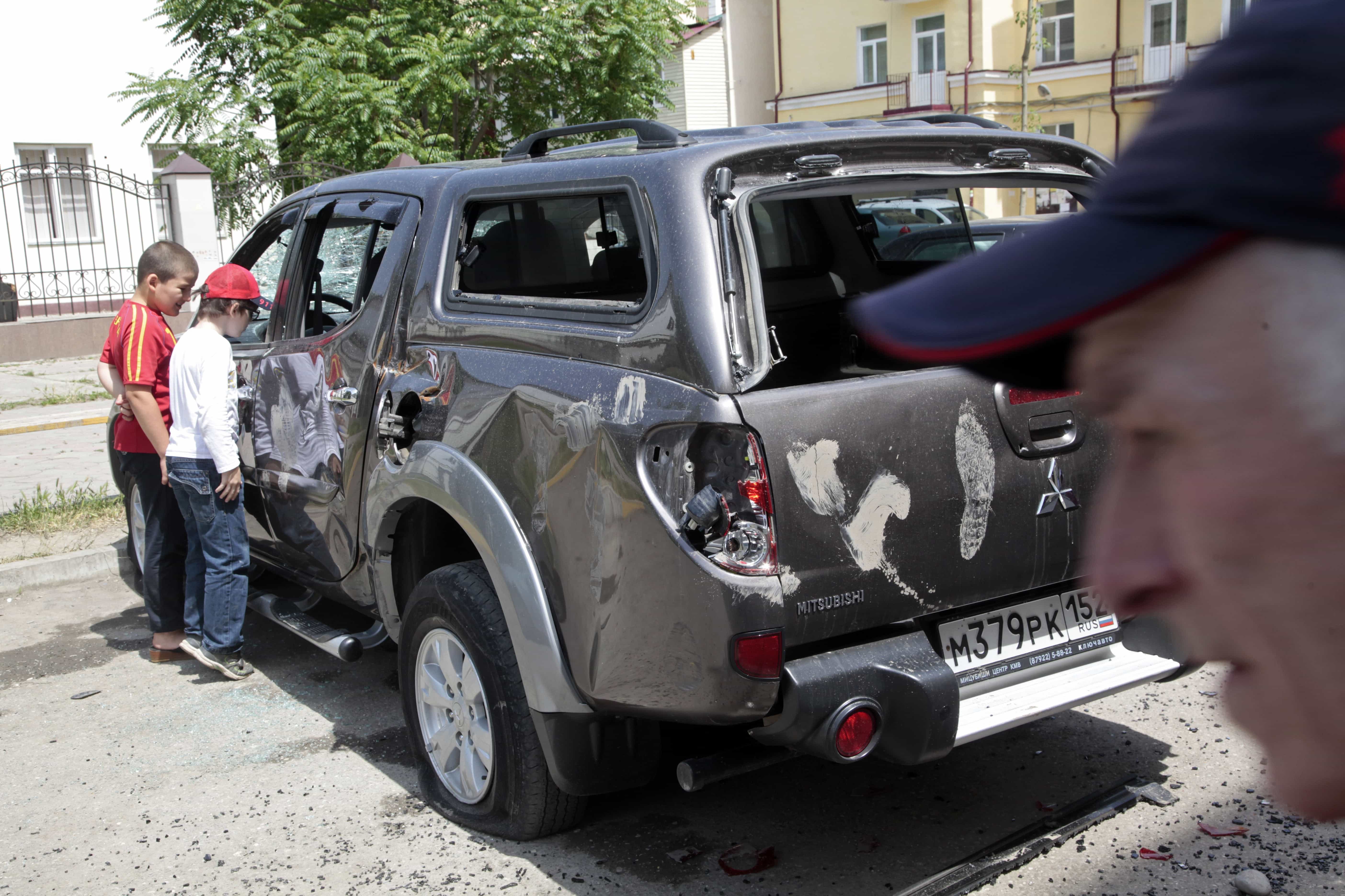 Children look into a damaged car, outside the office of the Committee Against Torture in Grozny, Russia, 3 June 2015. Masked men bashed their way into the office of the Committee against Torture in the regional Chechen capital of Grozny last year, smashing furniture and sending the occupants fleeing through the windows, their colleagues said. , AP Photo/Musa Sadulayev, file