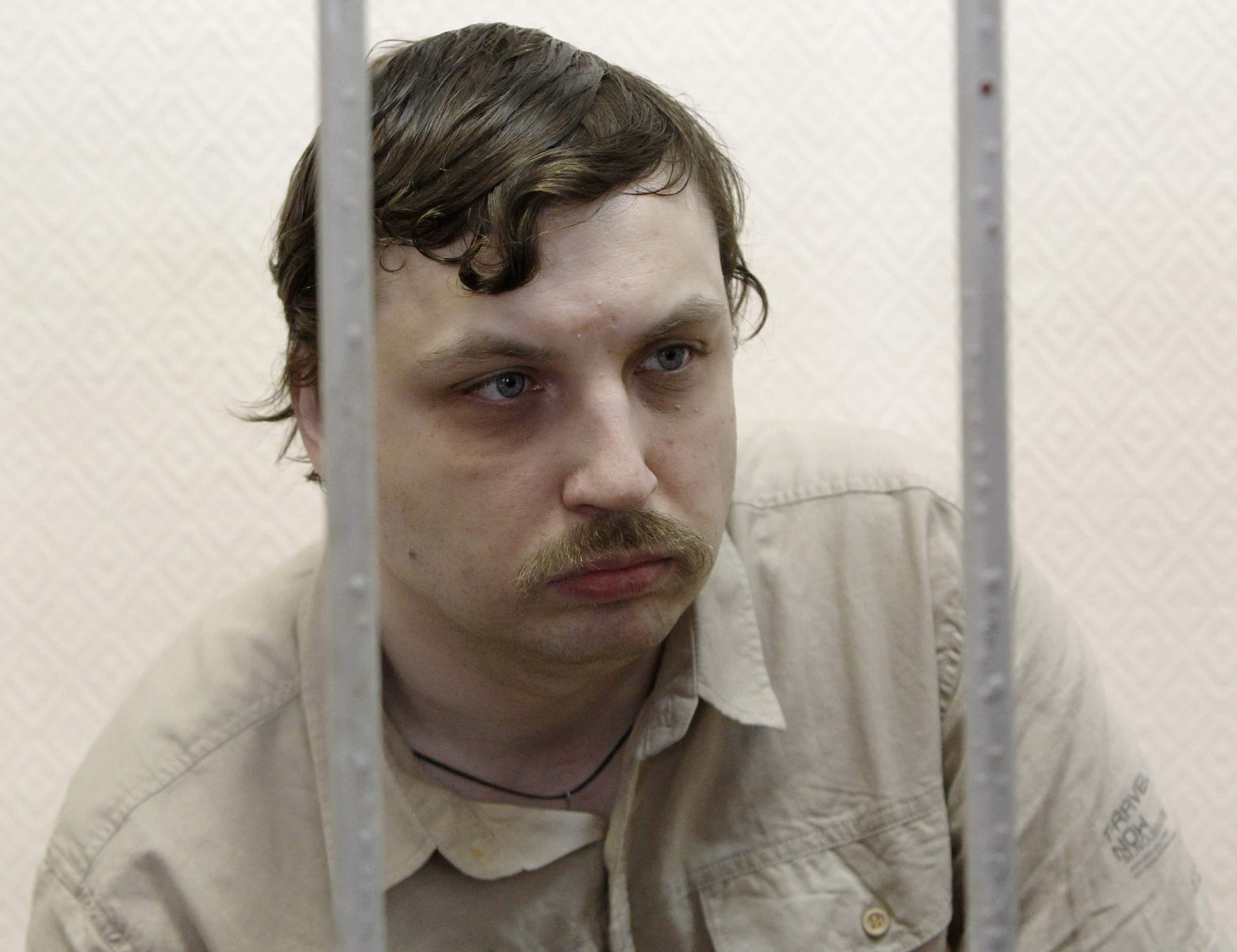 Mikhail Kosenko sits inside a defendants' cage during a court hearing in Moscow, 29 May 2013., REUTERS/Maxim Shemetov