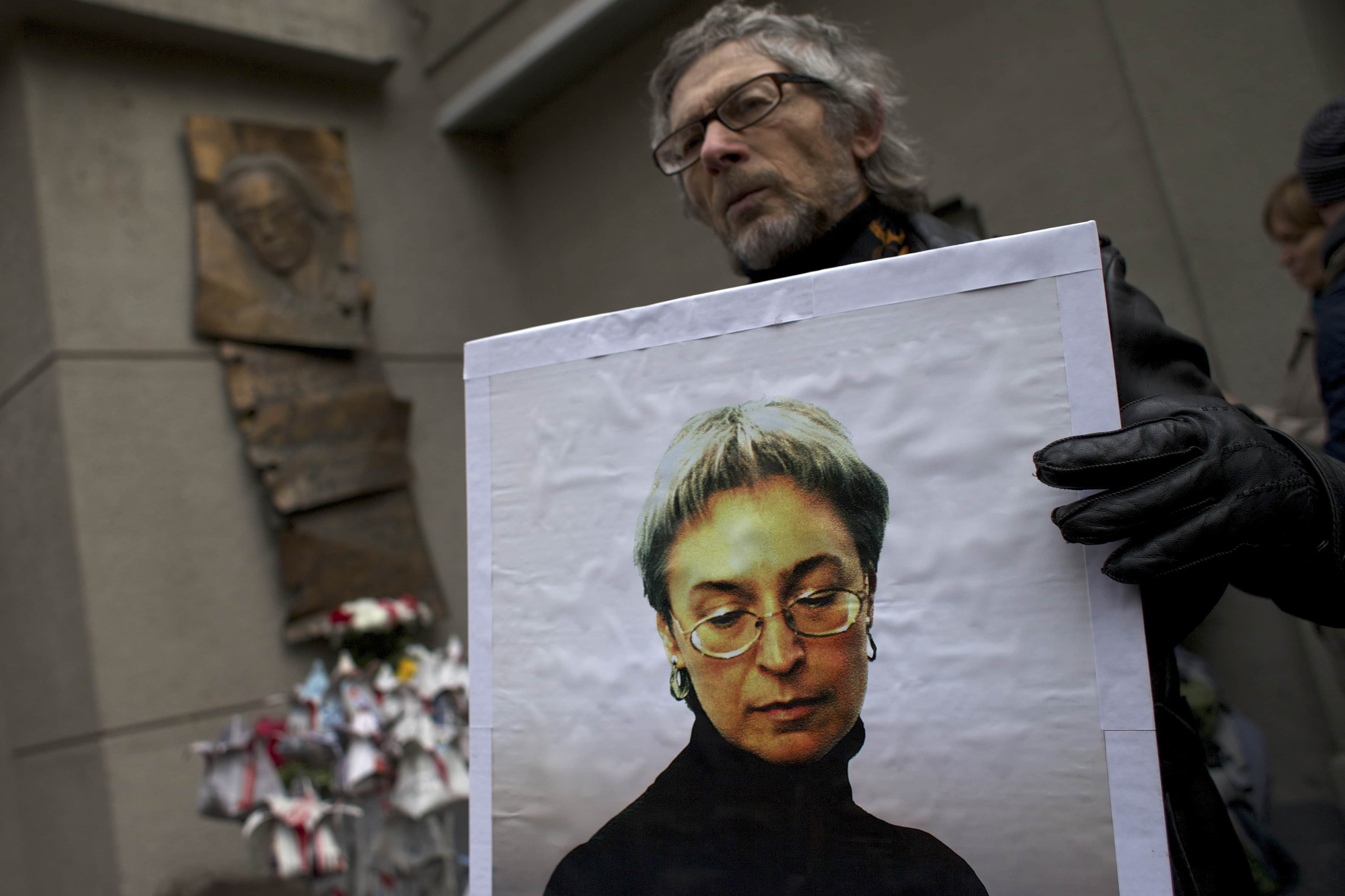 A man holds a portrait of Anna Politkovskaya, as people lay flowers made from newspapers to pay respect to Politkovskaya outside the "Novaya Gazeta" head office in Moscow, 7 October 2014, AP Photo/Ivan Sekretarev