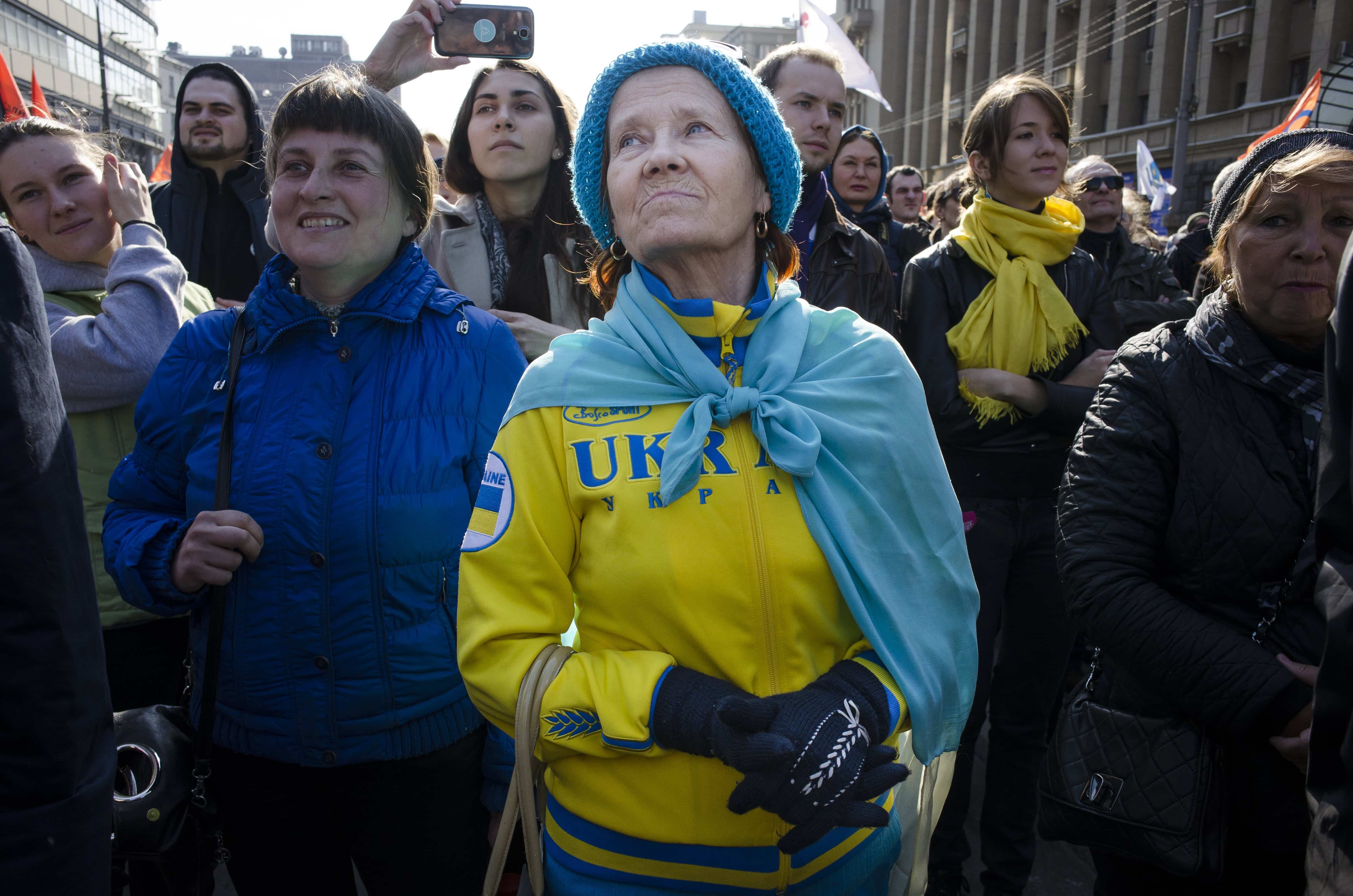 A woman wearing clothes in the color of the Ukrainian flag listens to a speaker during a rally against pro-Putin media in Moscow, 13 April 2014., AP Photo/Alexander Zemlianichenko