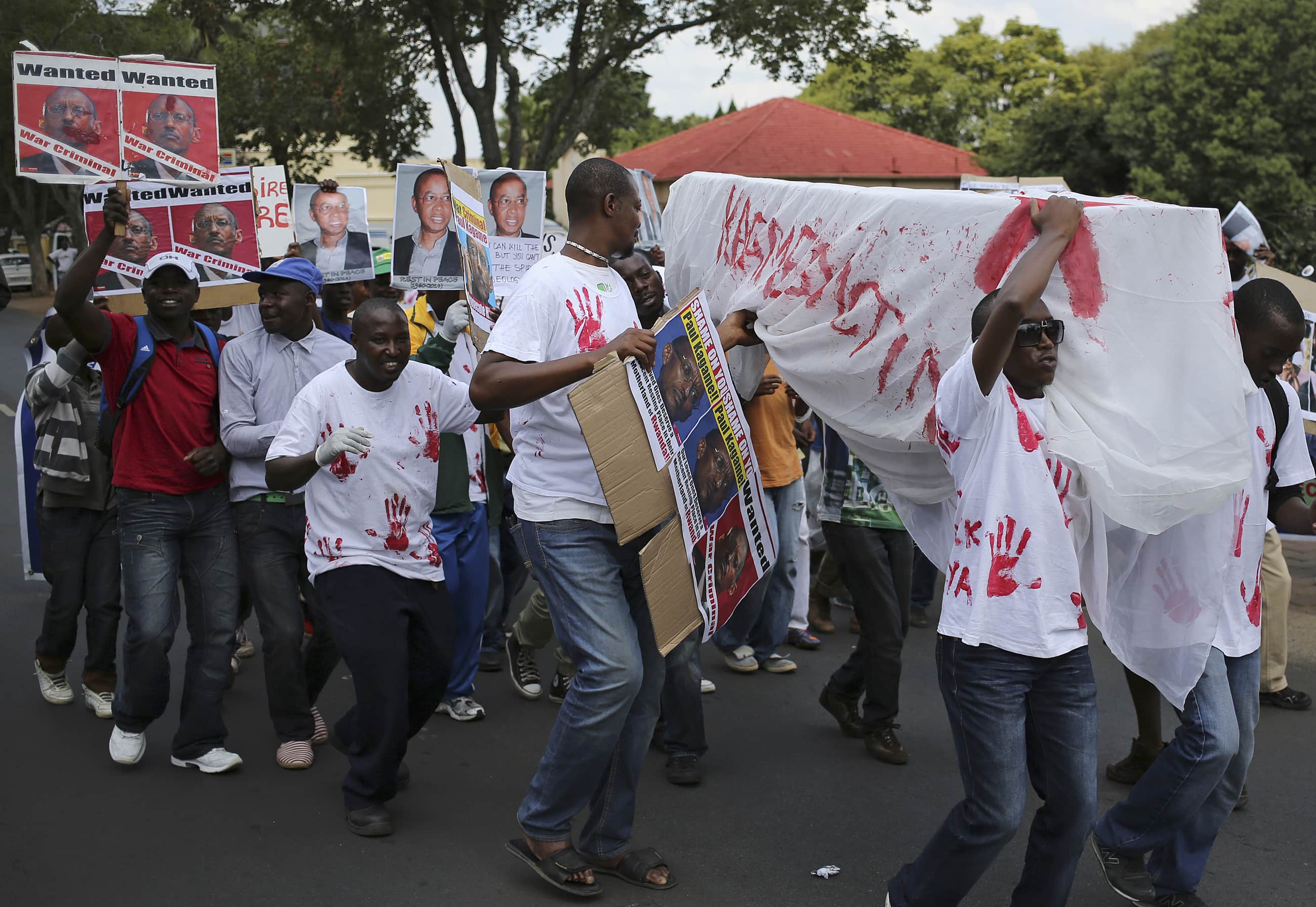 Supporters of the Rwanda National Congress, an opposition party that exiled former Rwandan intelligence chief Patrick Karegeya helped formed in 2011, carry a makeshift coffin as they protest outside the Rwandan embassy in Pretoria after Karegeya was found murdered in a Johannesburg hotel room, 9 January 2014., REUTERS/Siphiwe Sibeko