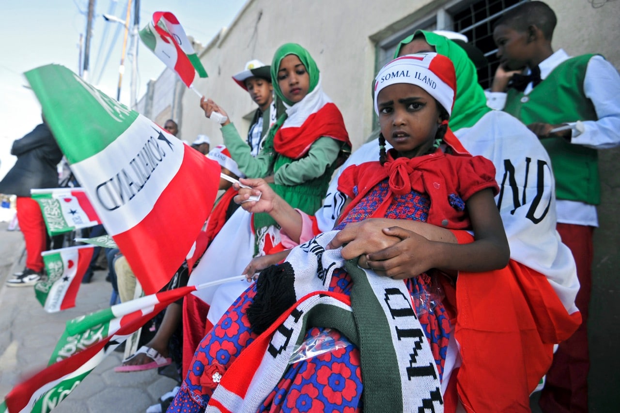 People wave flags as Somaliland soldiers and other military personnel march in an Independence day celebration parade in the capital, Hargeisa, 18 May 2016 , MOHAMED ABDIWAHAB/AFP/Getty Images