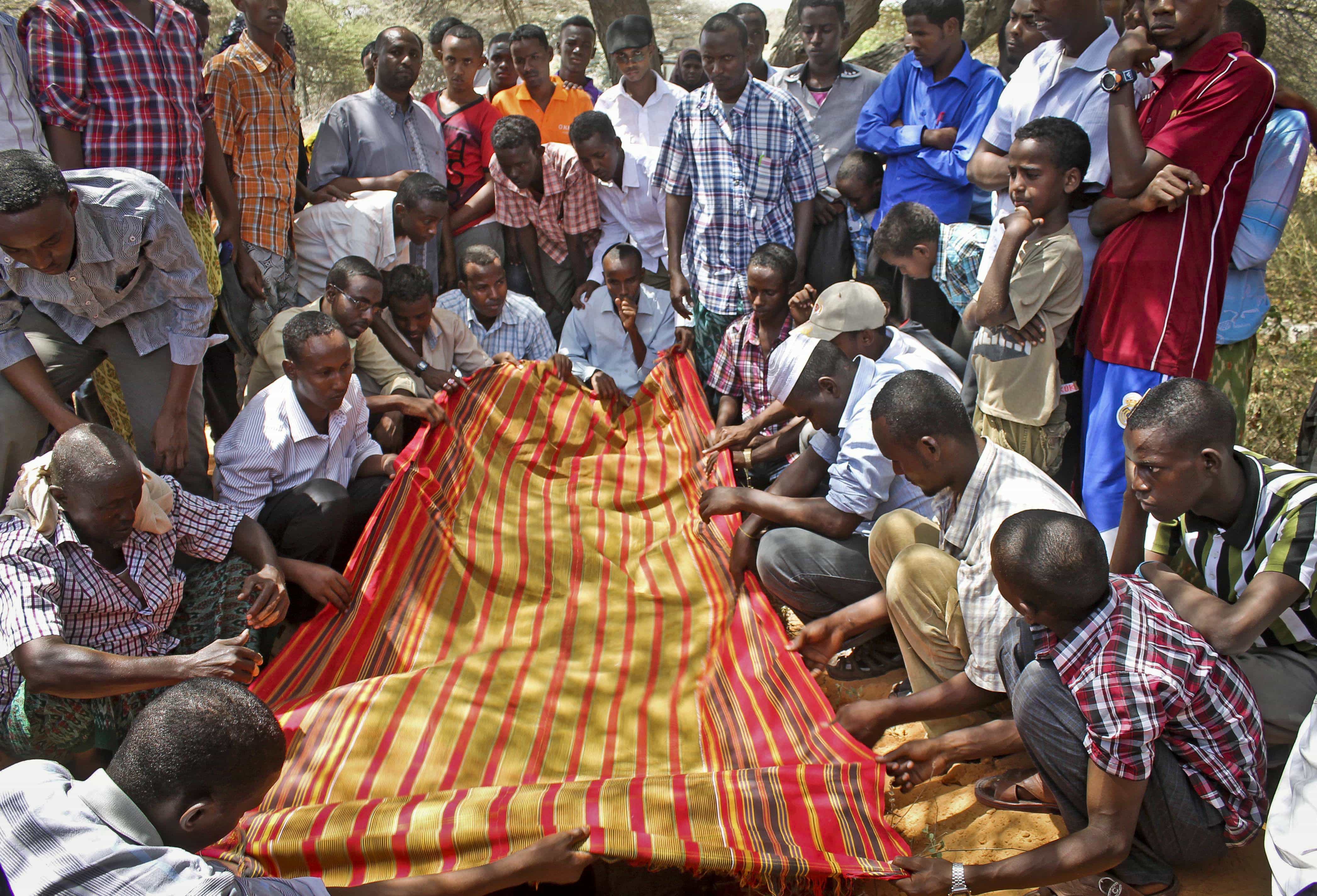 Mourners gather at the grave of Somali radio producer Abdihared Osman Aden, who was shot dead by unknown gunmen, in Mogadishu, 18 January 2013., AP Photo/Farah Abdi Warsameh