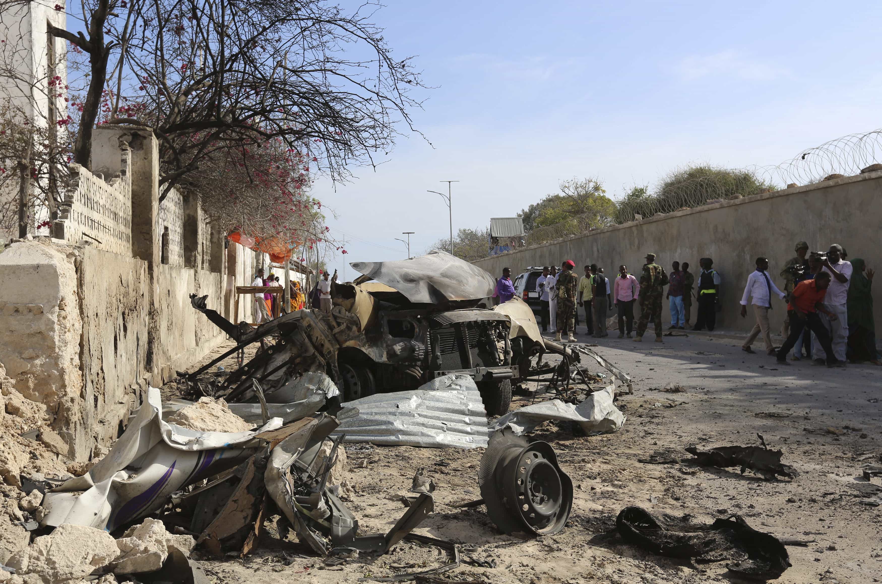 People look at the scene of a suicide attack next to the gate of the Presidential Palace in Mogadishu, 21 February 2014, REUTERS/Feisal Omar