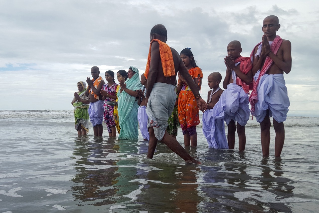 A Hindu family, forced to flee their village after armed masked men swarmed their homes, stand in prayer near the shore of the Andaman Sea in Sittwe, Myanmar, 8 October 2017, STRINGER/AFP/Getty Images