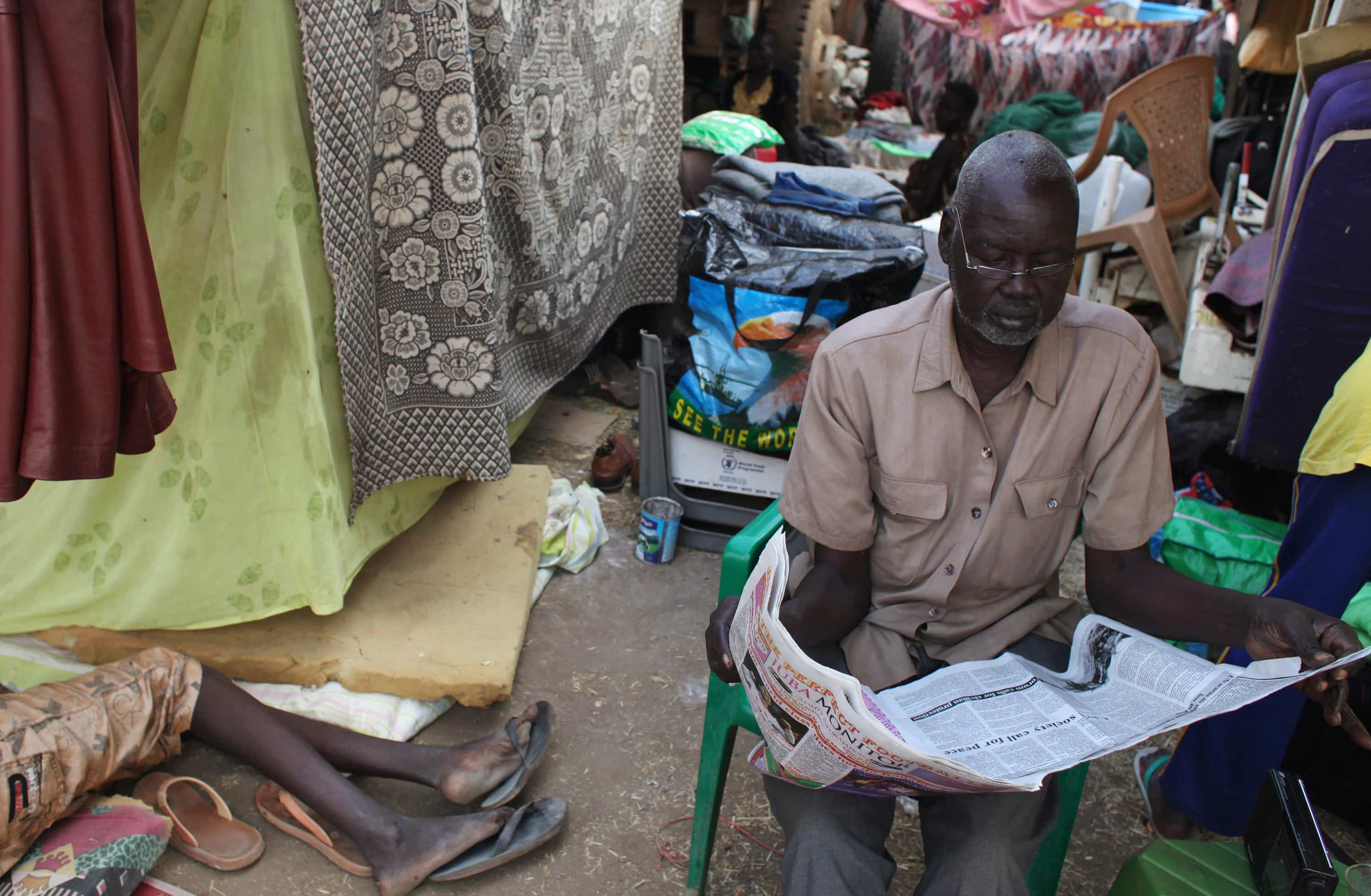 A displaced man reads a newspaper at Tomping camp, in Juba, South Sudan, 10 January 2014, REUTERS/Andreea Campeanu