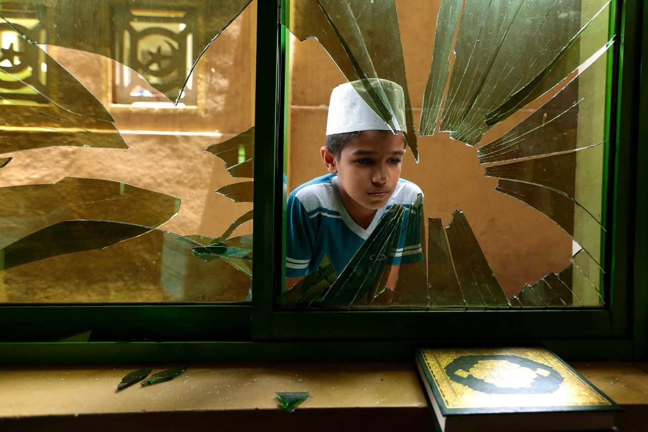 A boy looks through a broken window among the debris of a vandalized mosque in Digana, some 157 kms from Colombo, Sri Lanka, 9 March 2018, Tharaka Basnayaka/NurPhoto via Getty Images