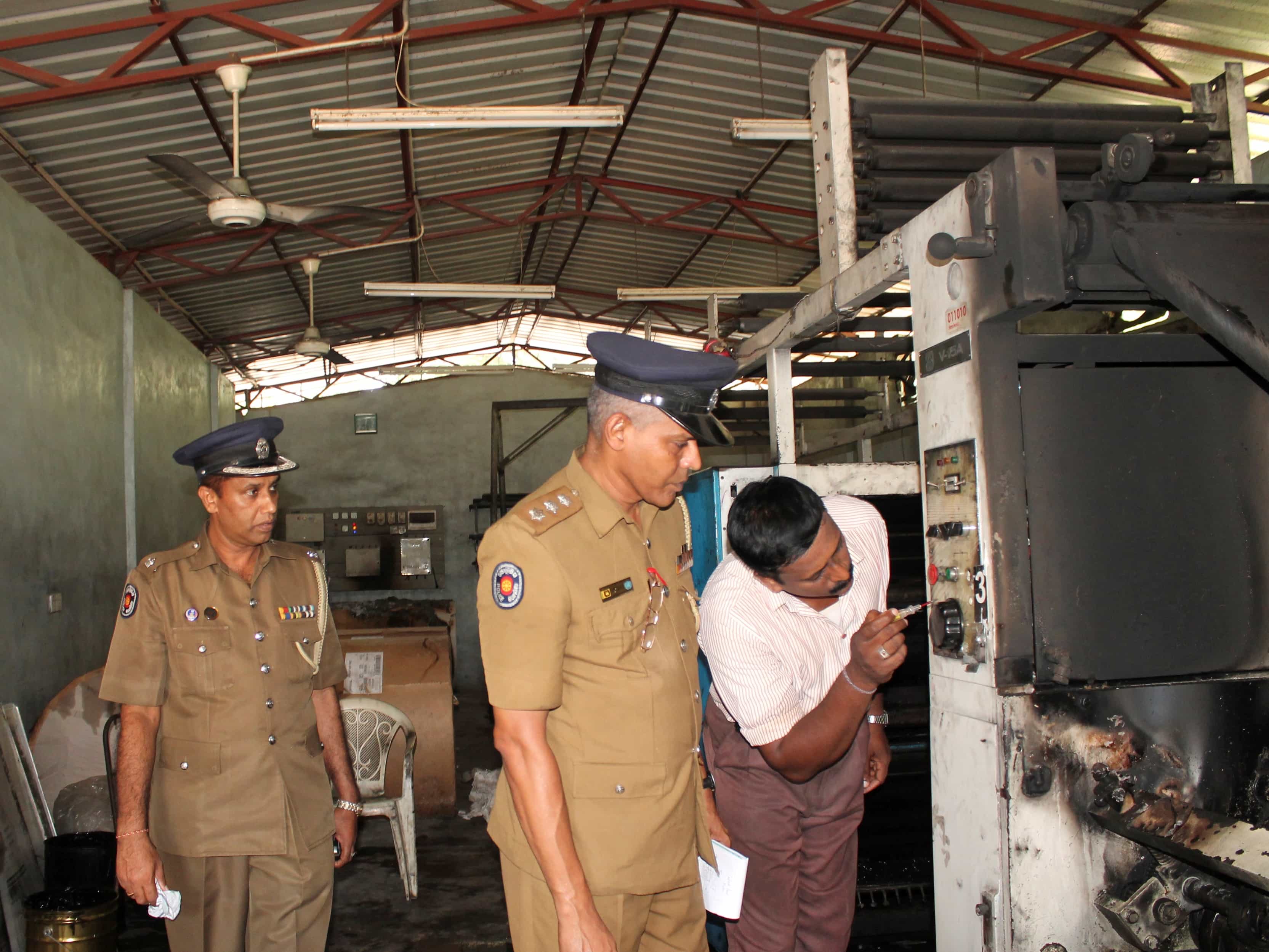 Police officers inspect burnt printing machines after an attack on the "Uthayan" printing press in Jaffna, REUTERS/Stringer