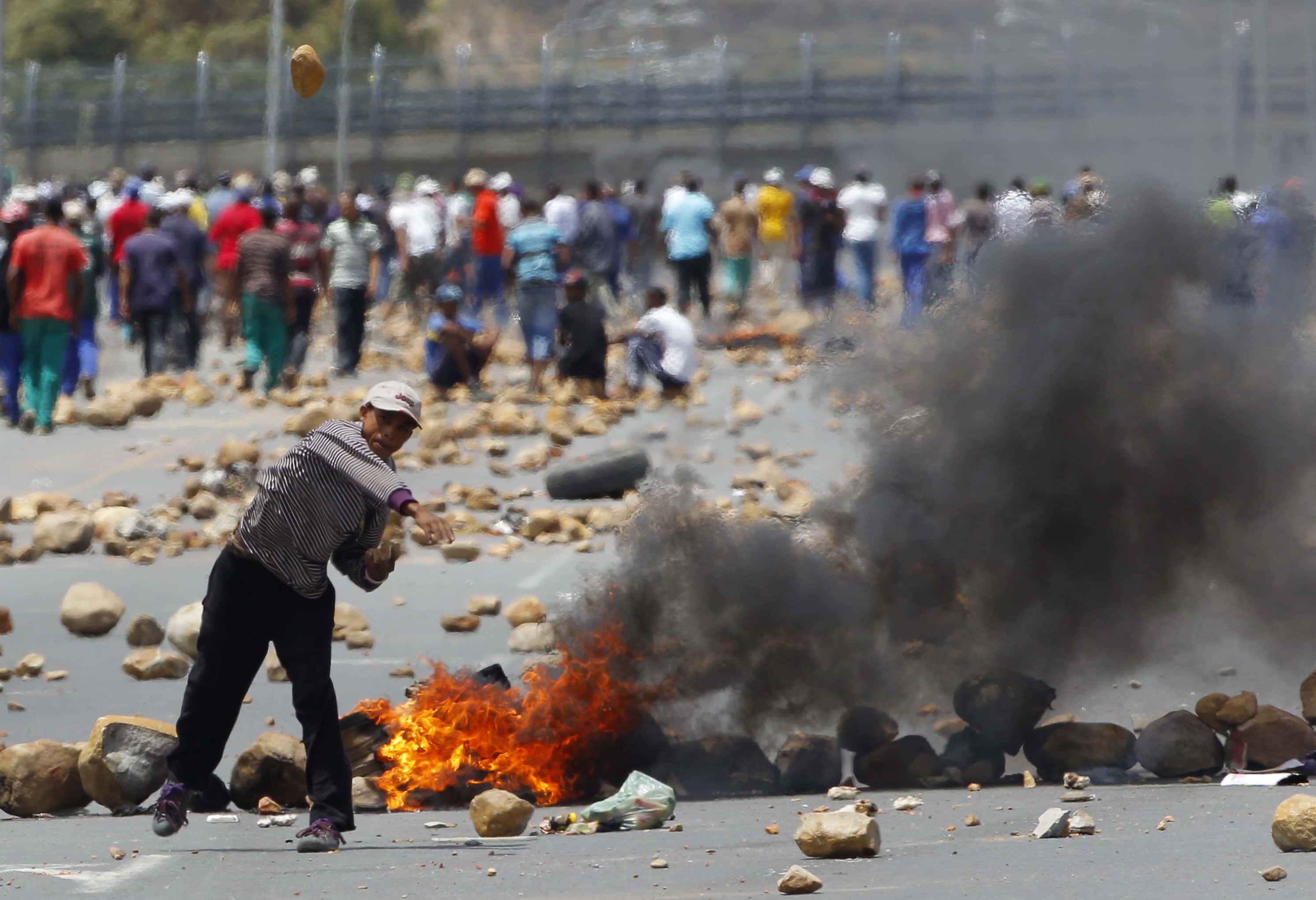 A protester throws a stone at the police during a strike by farm workers in De Doorns. Some journalists were attacked while covering the strike action., Reuters/Mike Hutchings