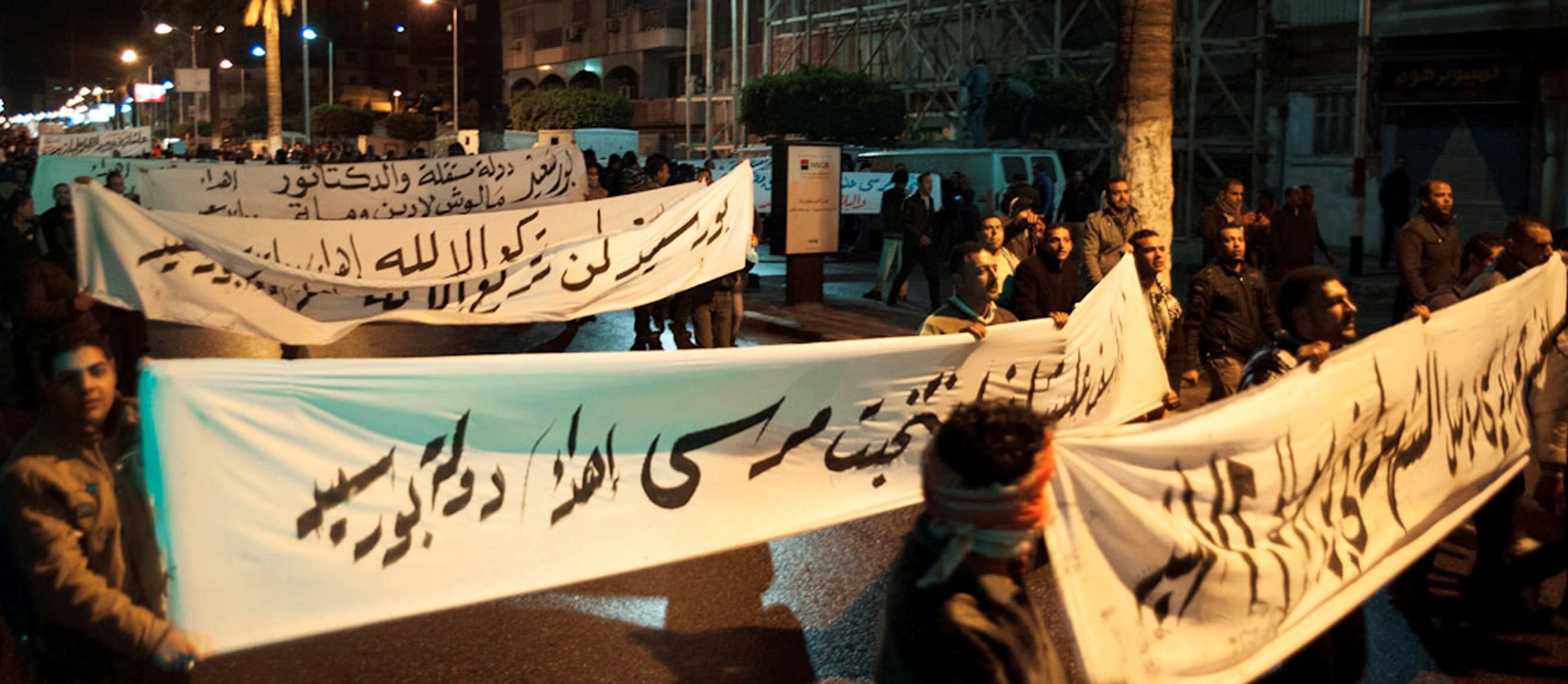 Egyptian protesters defied a nighttime curfew in restive towns along the Suez Canal, carrying banners as they marched on 28 January 2013 ignoring the emergency rule imposed by President Mohammad Morsi, REUTERS/Stringer