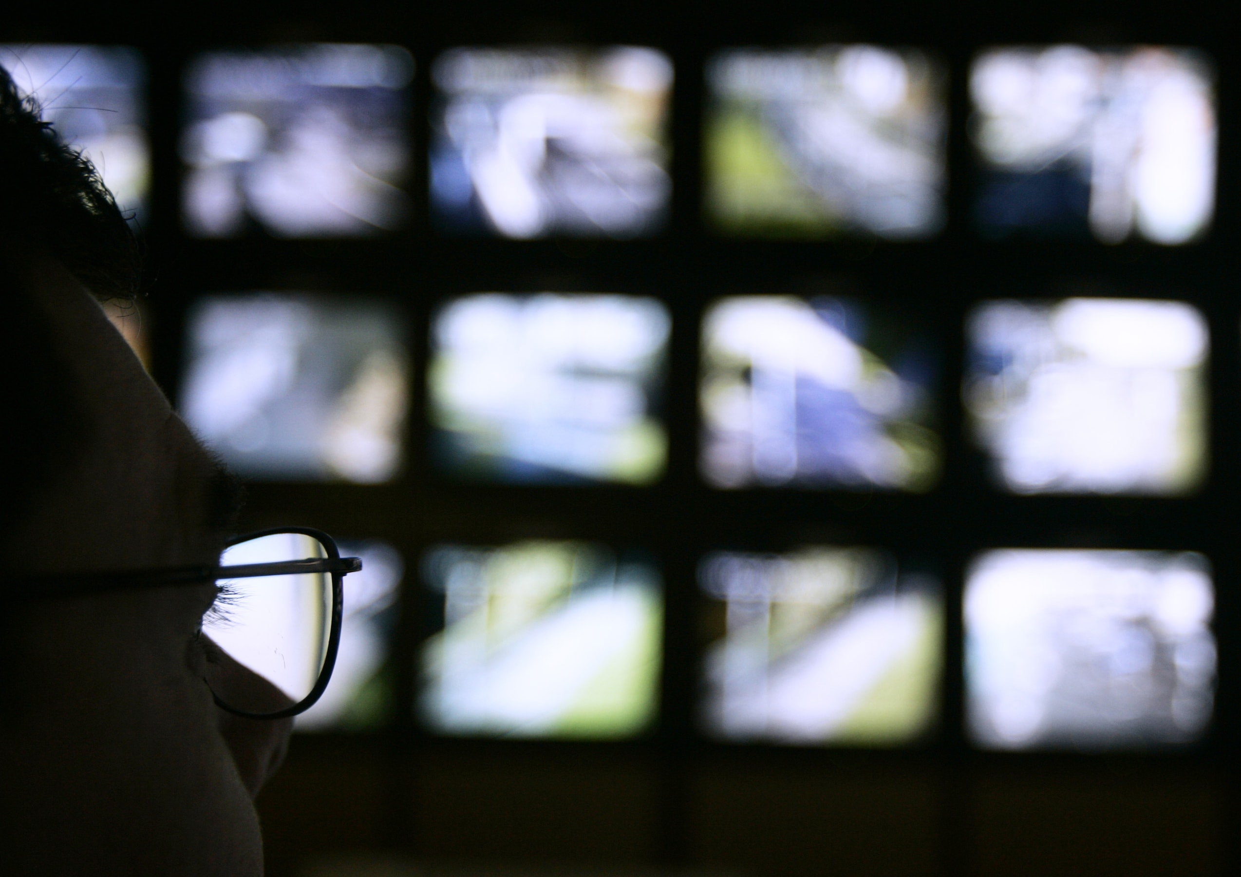 A surveillance monitoring expert watches a bank of screens showing images from Edinburgh City Council's network of CCTV cameras in Edinburgh, Scotland in 2006, REUTERS/David Moir