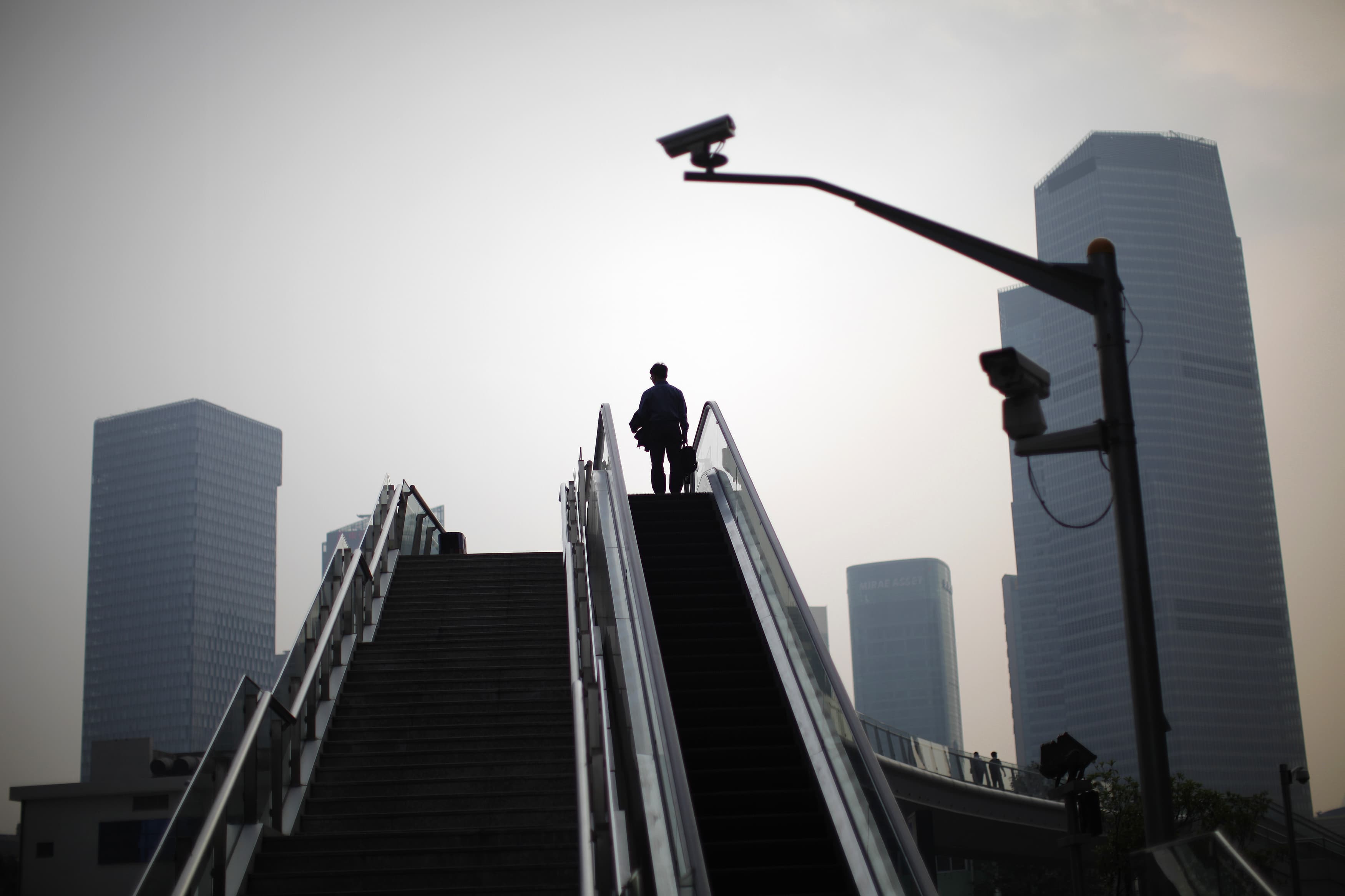 A man stands on an escalator at the financial district of Pudong in Shanghai May 6, 2011, REUTERS/Carlos Barria