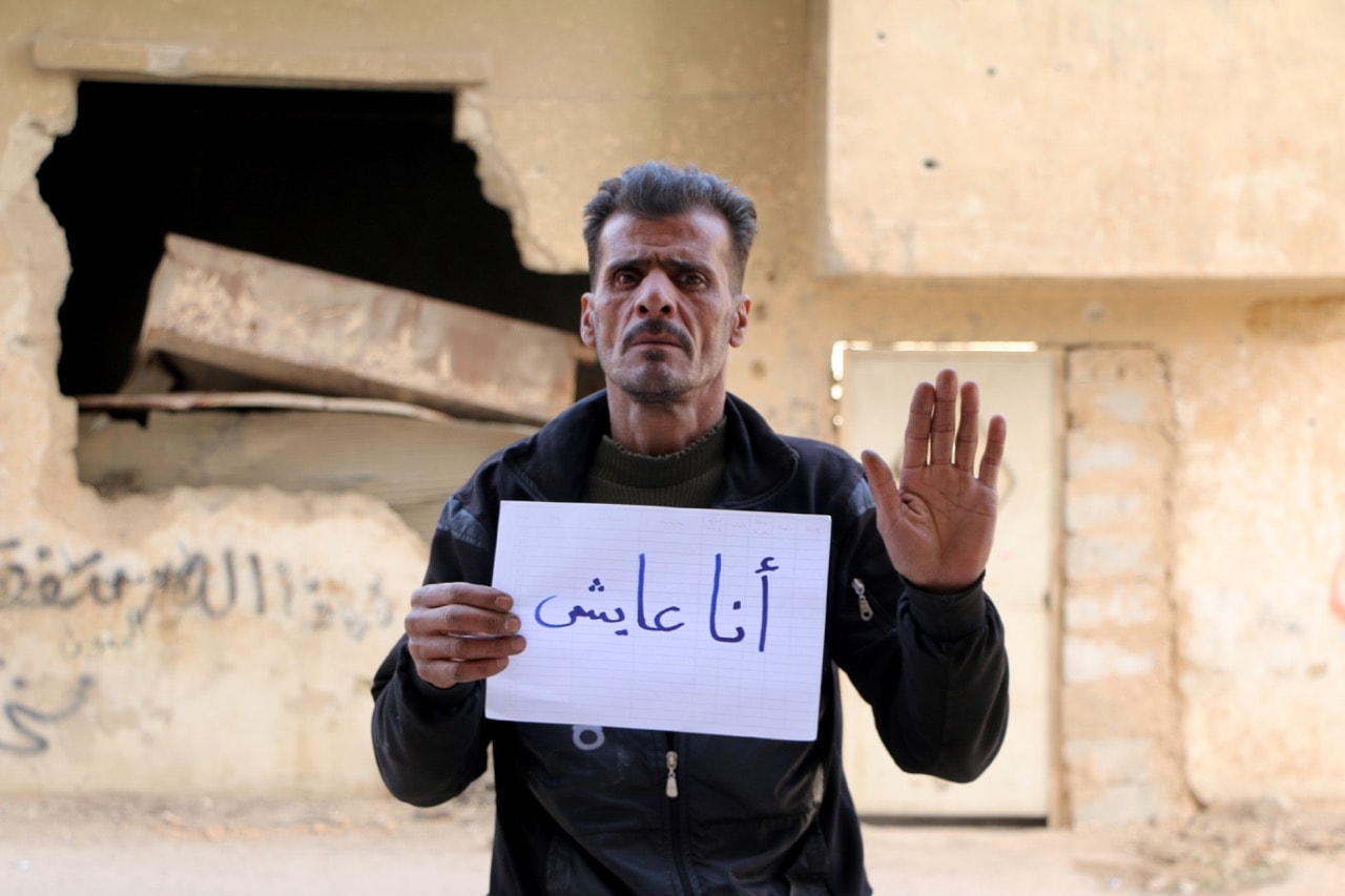 A man poses for a photo for the social media campaign #Iamstillalive, to raise awareness about the humanitarian crisis in Eastern Ghouta of Damascus, Syria, 2 March 2018, Khaled Akasha/Anadolu Agency/Getty Images