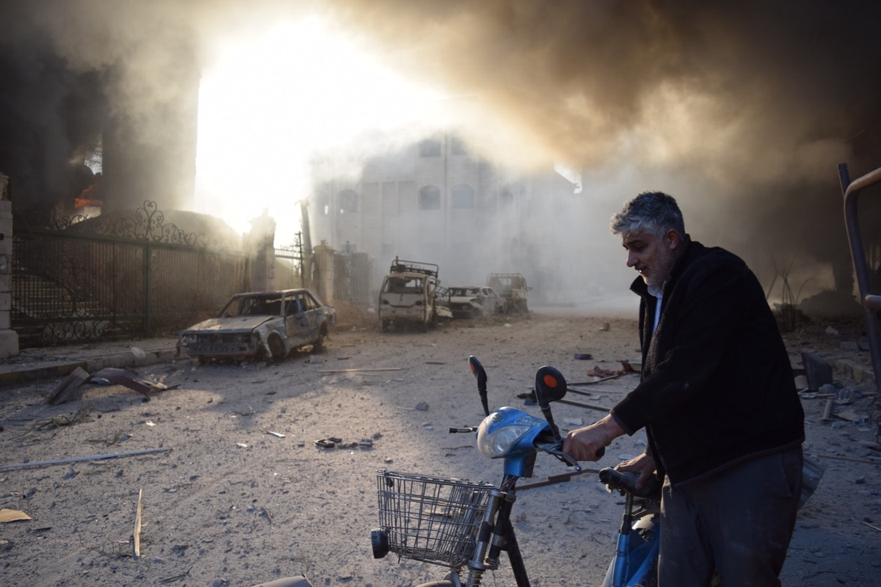 A citizen escapes from the scene with a motorbike after Assad regime forces carried out an airstrike over Douma town in Eastern Ghouta, Syria, 24 February 2018, Mouneb Abu Taim /Anadolu Agency/Getty Images