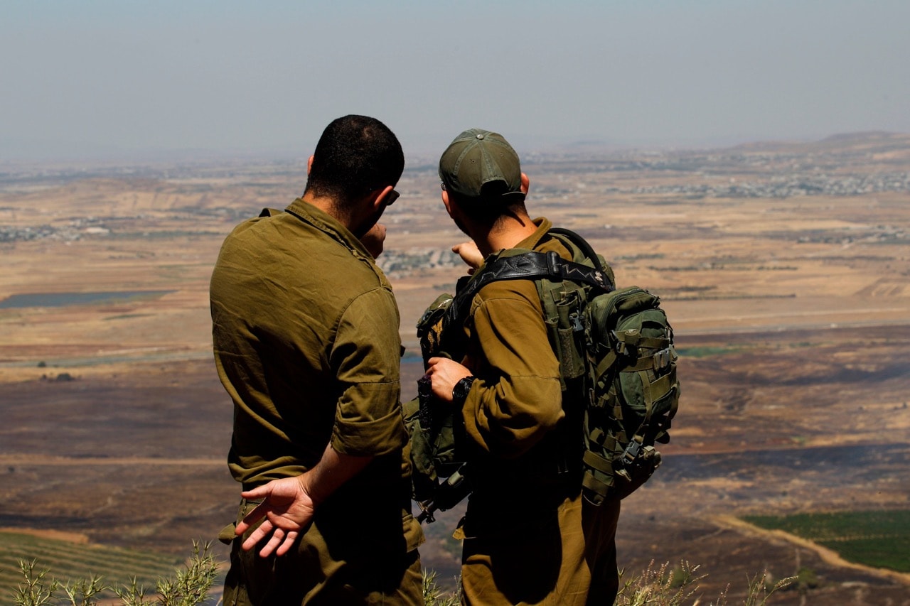 Israeli soldiers at an army base in the Israeli-annexed Syrian Golan Heights look out across the southwestern Syrian province of Quneitra, visible across the border, 7 July 2018, JALAA MAREY/AFP/Getty Images