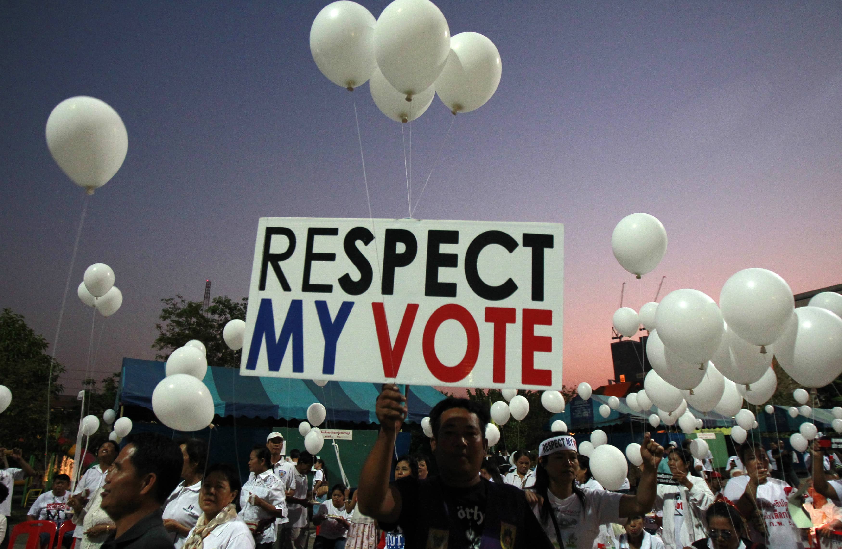 Pro-government supporters hold a placard and white balloons during an election campaign in Nonthaburi province, on the outskirts of Bangkok, 31 January 2014, REUTERS/Chaiwat Subprasom