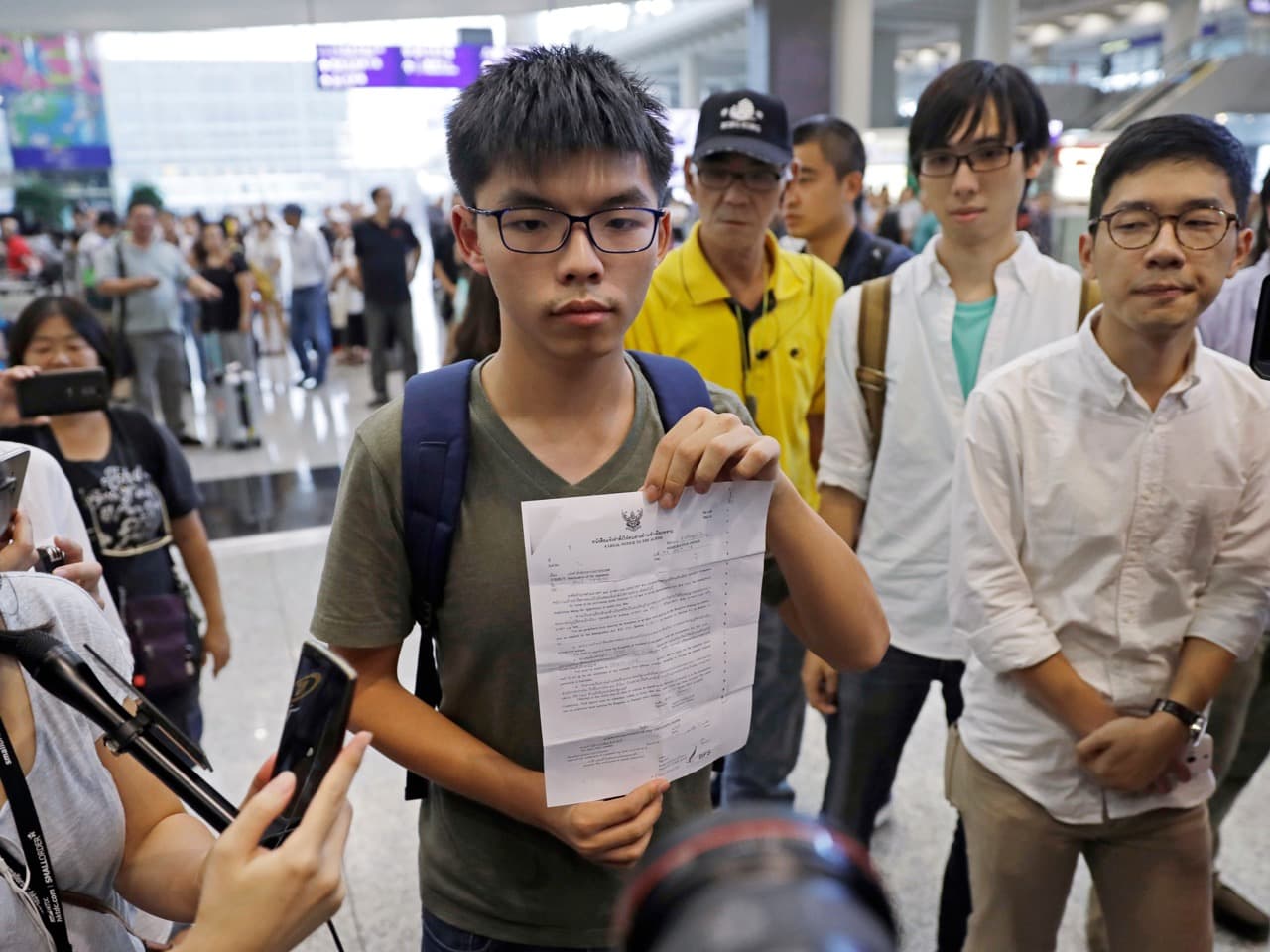 Activist Joshua Wong, center, shows the letter from the Thailand Immigration office upon arriving at Hong Kong airport from Bangkok, 5 October 2016, AP Photo/Kin Cheung