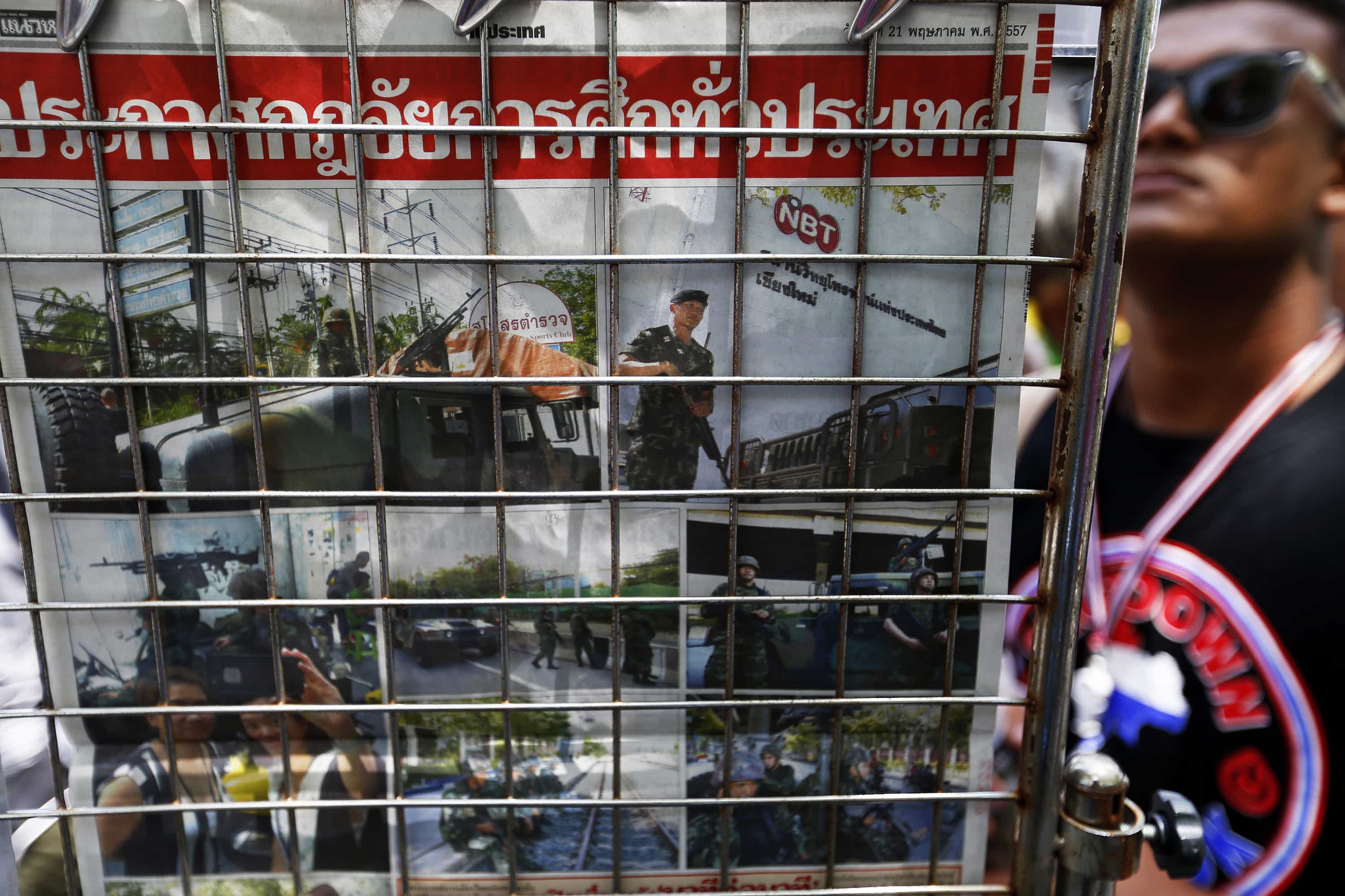 An anti-government protester reads morning papers displayed inside the encampment in central Bangkok, 21 May 2014, REUTERS/Damir Sagolj