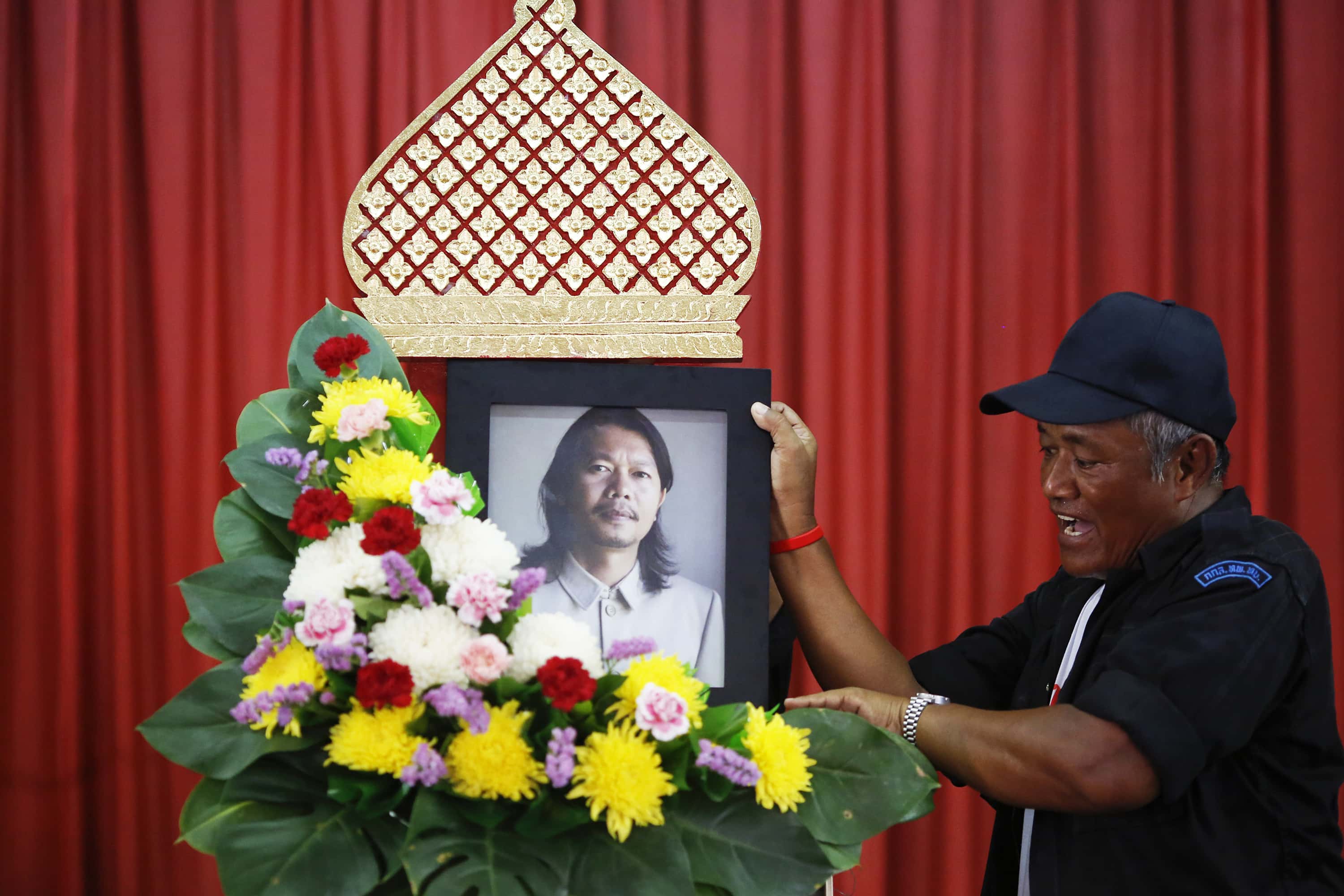 A man places a portrait of Kamol Duangphasuk, who was killed a day before, as his body is prepared for a funeral at a Buddhist temple in Bangkok, 24 April 2014, REUTERS/Damir Sagolj