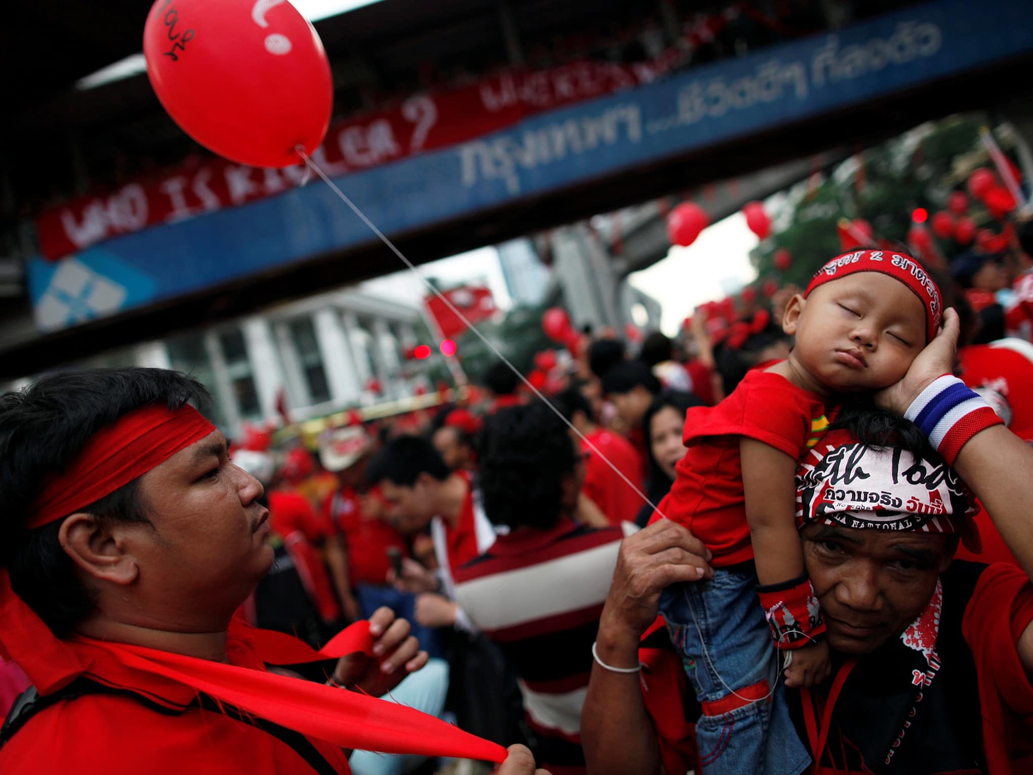 An anti-government "'red shirt"' protester carries his sleeping son through the crowd during a rally in Bangkok, 19 September 2010, REUTERS/Damir Sagolj