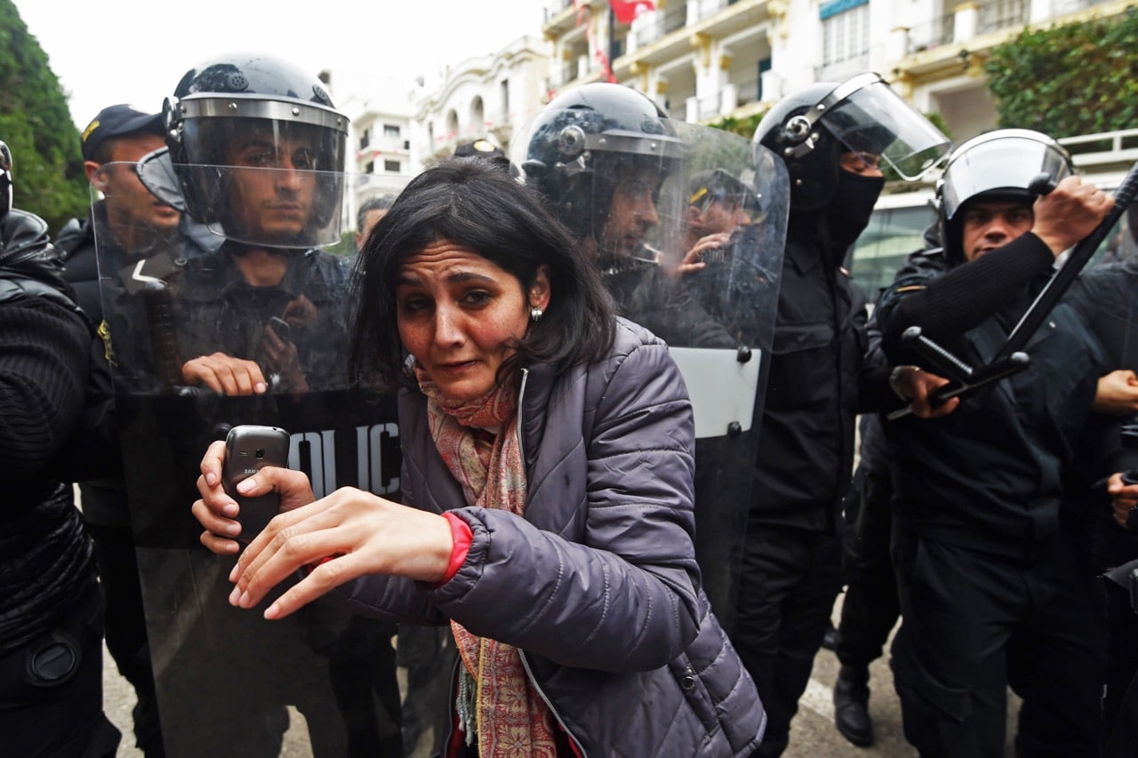 A protester is seen in front of police officers standing guard during a demonstration against the government and price hikes in Tunis, Tunisia, 9 January 2018, FETHI BELAID/AFP/Getty Images