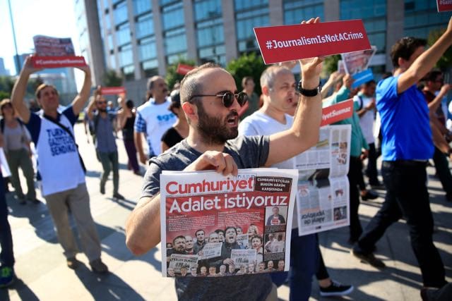 Activists, one holding today's copy of "Cumhuriyet" newspaper, march to a court in Istanbul, on 24 July 2017, to protest against the trial of the paper's journalists and staff, AP Photo/Lefteris Pitarakis