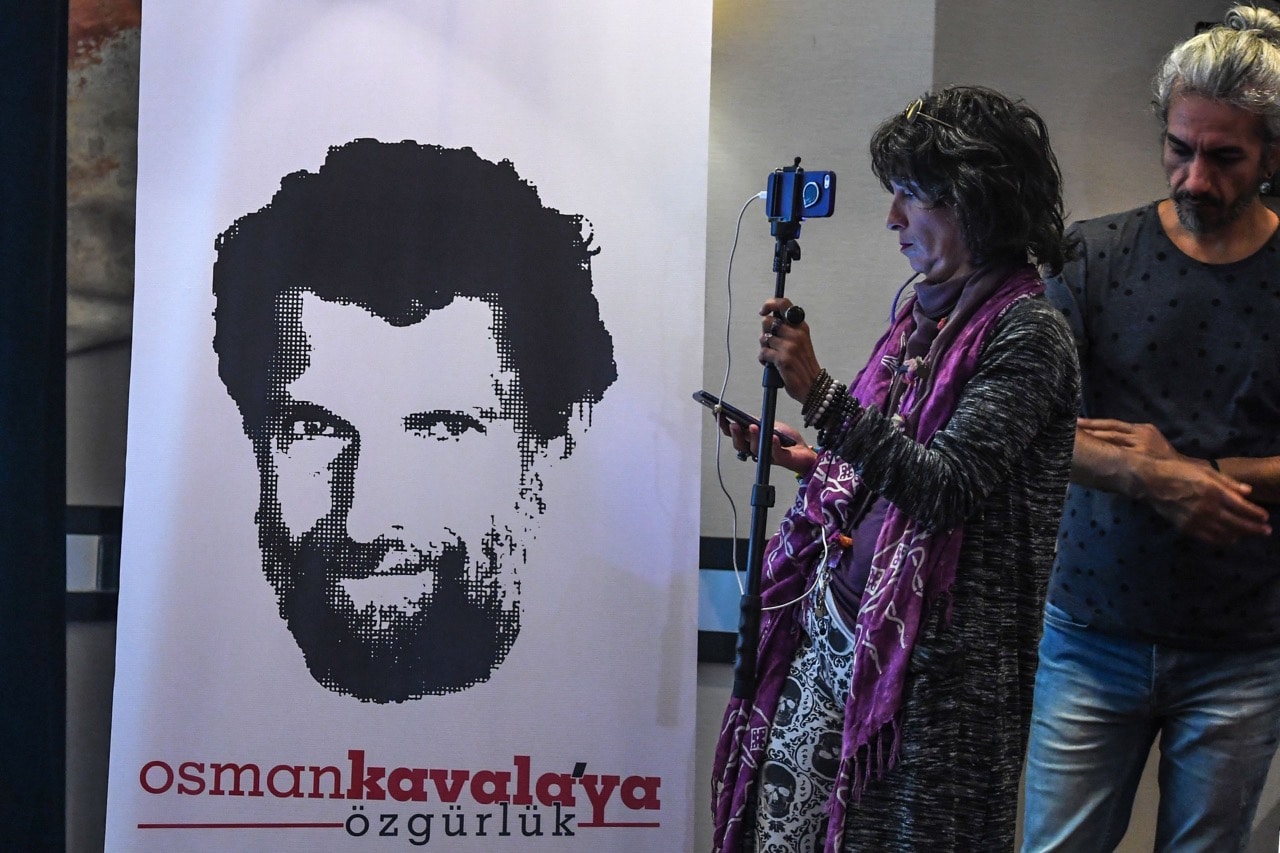 A journalist stands in front of a poster featuring Osman Kavala during a press conference by his lawyers, in Istanbul, Turkey, 31 October 2018, OZAN KOSE/AFP/Getty Images