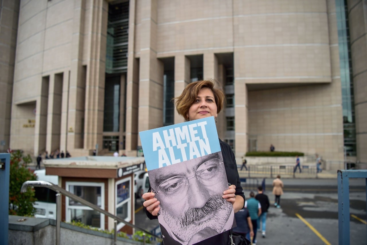 A journalist poses with a portrait of Ahmet Altan on 19 June 2017 in front of an Istanbul courthouse where 17 suspects, including jailed journalists Nazli Ilicak, Ahmet Altan and Mehmet Altan, were due to appear, OZAN KOSE/AFP/Getty Images